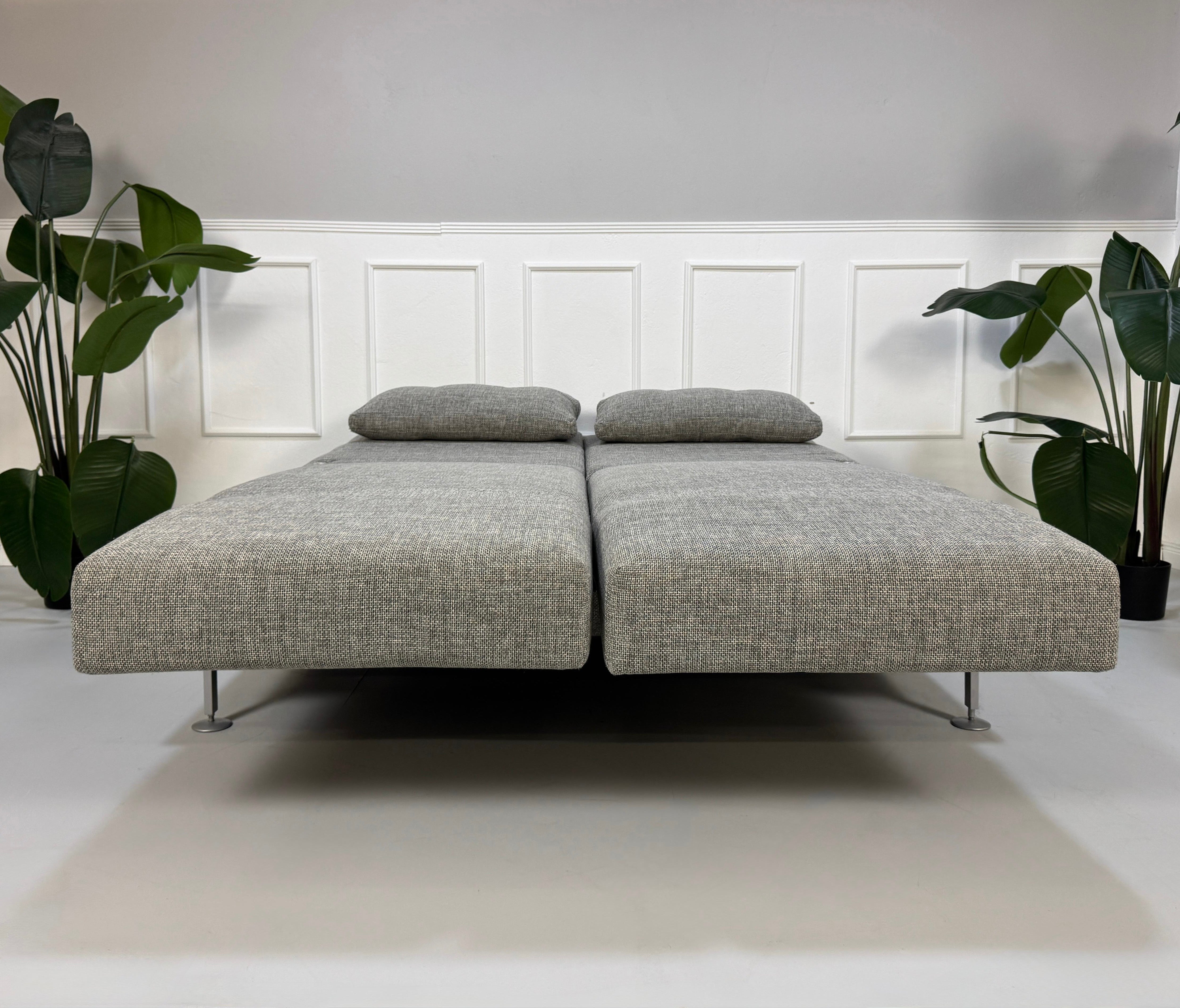 Refurbished graues Brühl Moule Designer Stoff Sofa vor einer Wand, stilvoll und modern eingerichtet.