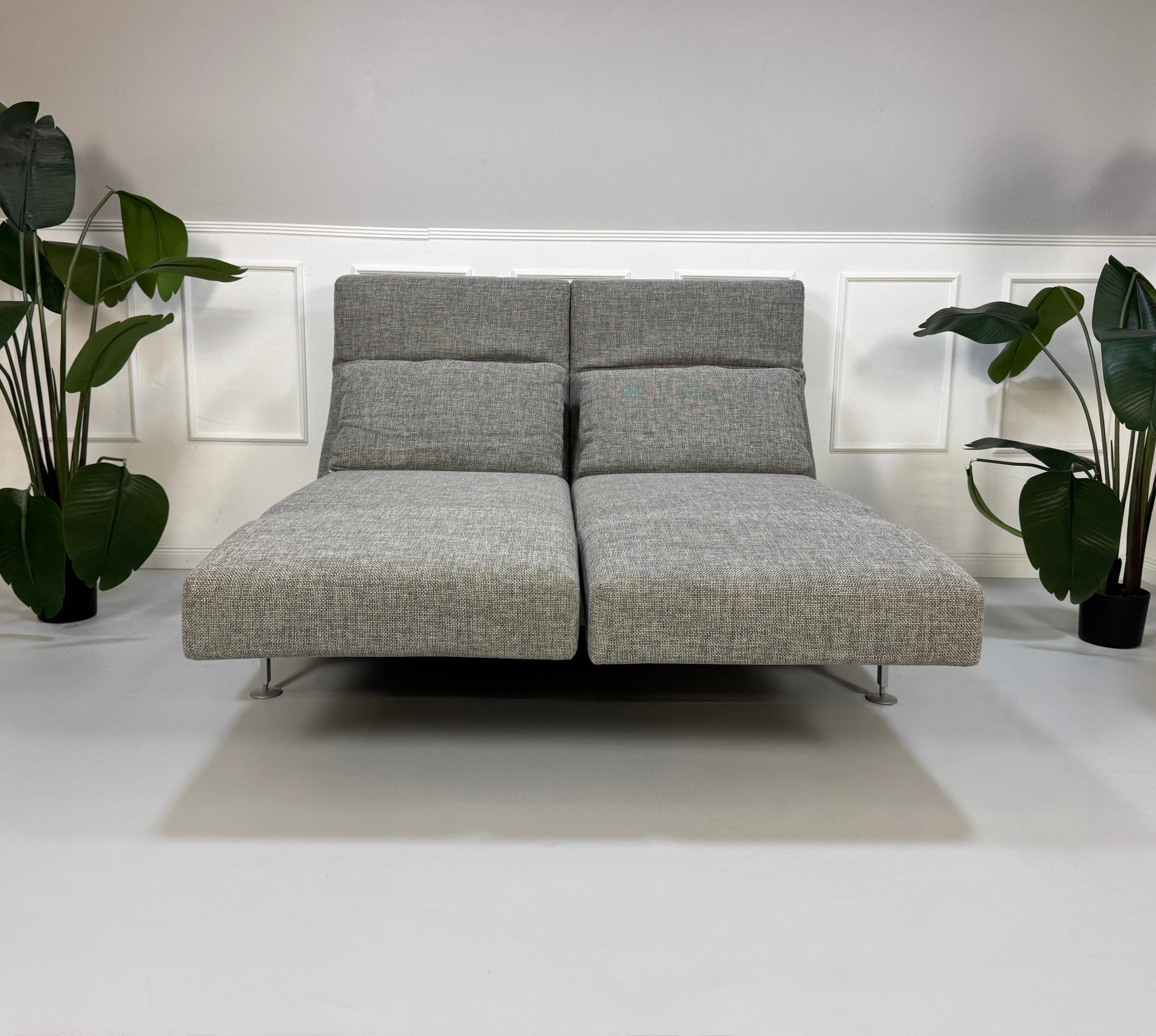 Refurbished graues Brühl Moule Designer Stoff Sofa vor einer Wand, stilvoll und modern eingerichtet.