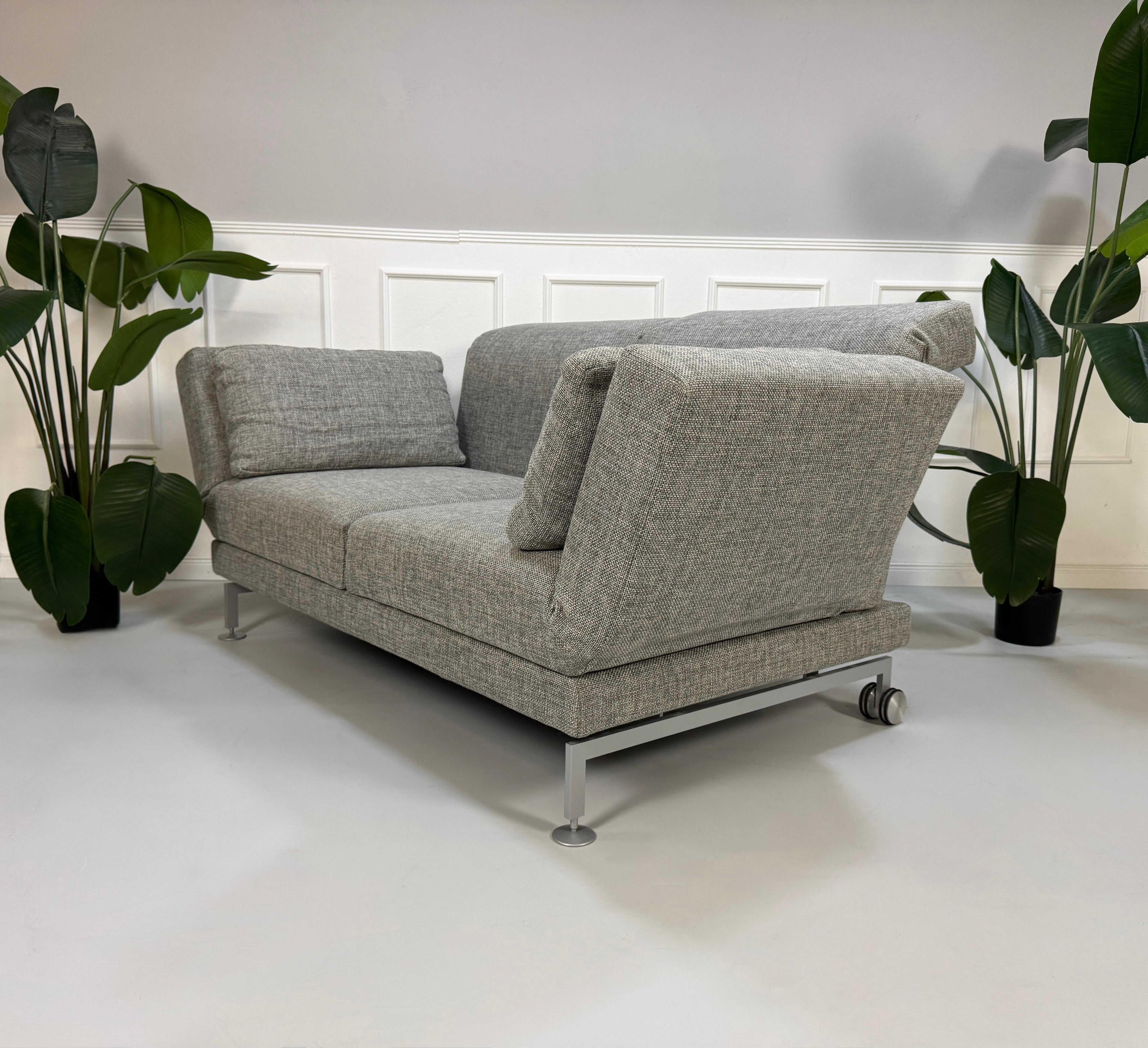 Refurbished graues Brühl Moule Designer Stoff Sofa vor einer Wand, stilvoll und modern eingerichtet.