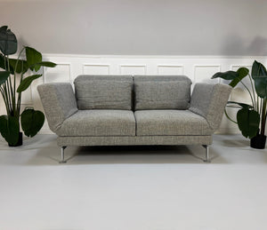 Refurbished graues Brühl Moule Designer Stoff Sofa vor einer Wand, stilvoll und modern eingerichtet.