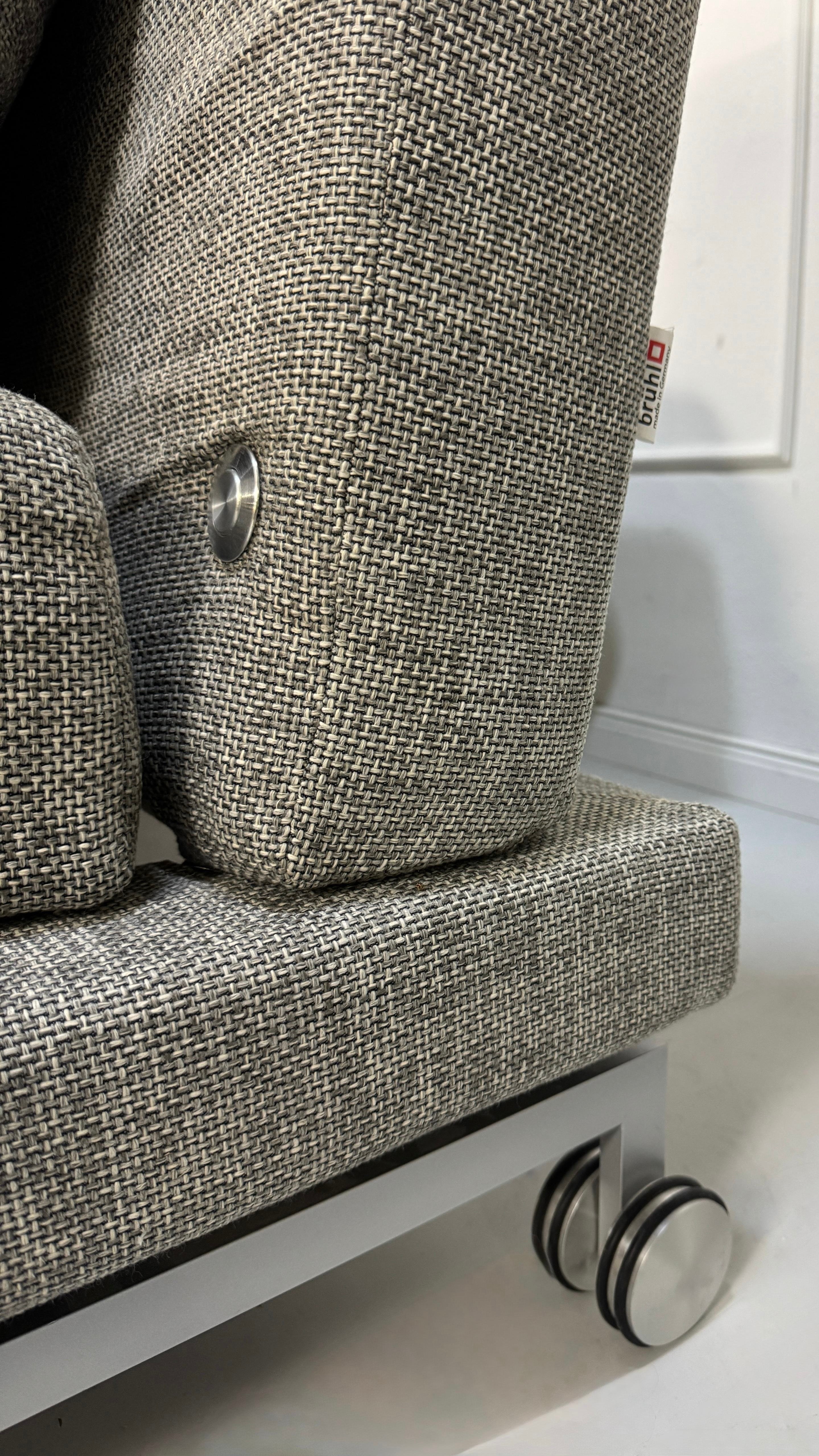Refurbished graues Brühl Moule Designer Stoff Sofa vor einer Wand, stilvoll und modern eingerichtet.