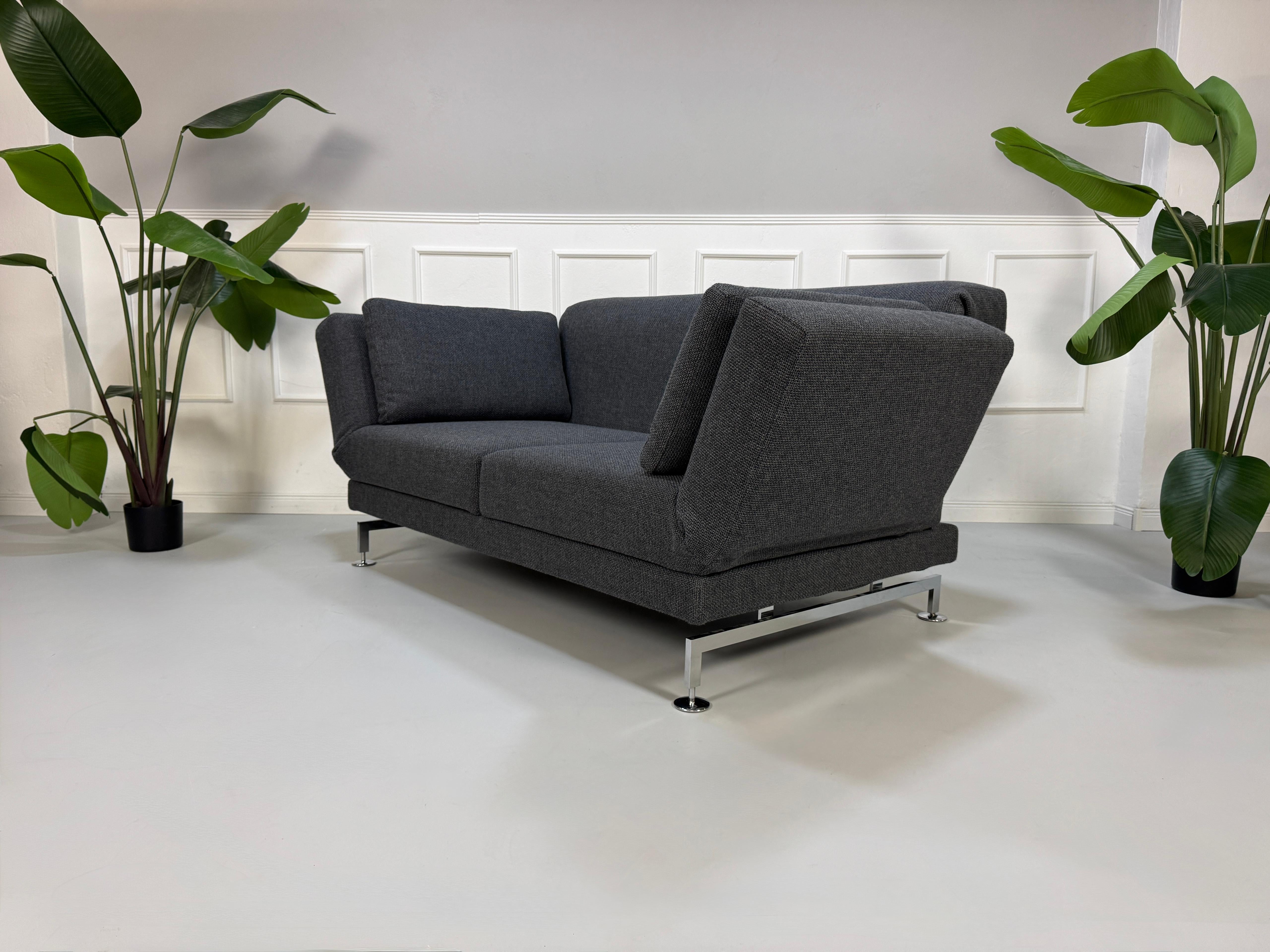 Graues Ausstellungsstück Brühl Moule Designer Stoff Sofa vor einer Wand, stilvoll und modern eingerichtet.