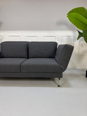Graues Ausstellungsstück Brühl Moule Designer Stoff Sofa vor einer Wand, stilvoll und modern eingerichtet.