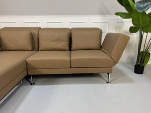 Gebrauchtes Brühl Moule Designer Leder Sofa in der Farbe Schlamm vor einer Wand, stilvoll und modern eingerichtet.