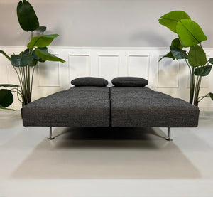 Anthrazit Brühl Moule Small Designer Stoff Sofa vor einer Wand, stilvoll und modern eingerichtet.