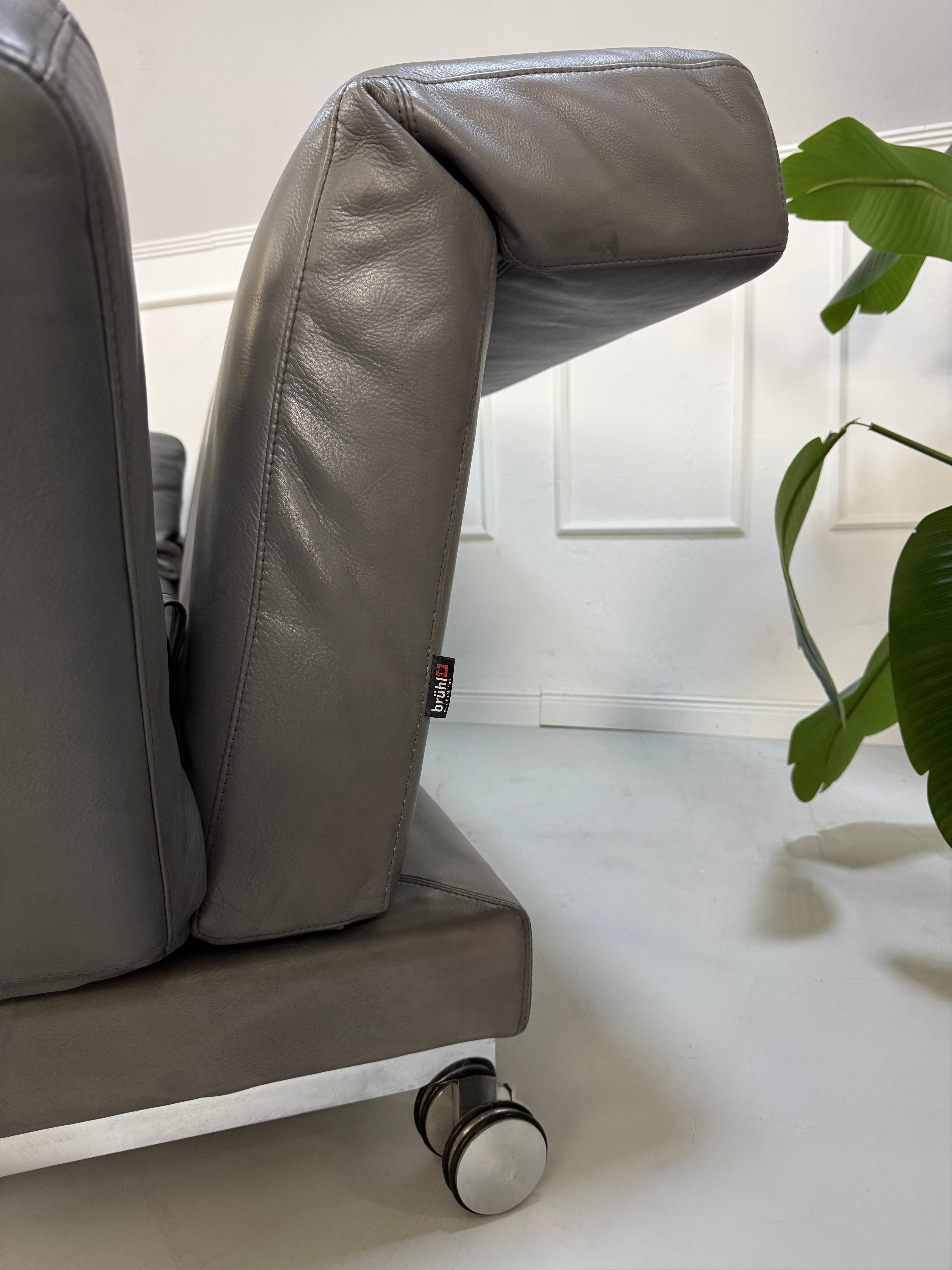Refurbished graues Brühl Moule Designer Leder Sofa vor einer Wand, stilvoll und modern eingerichtet.
