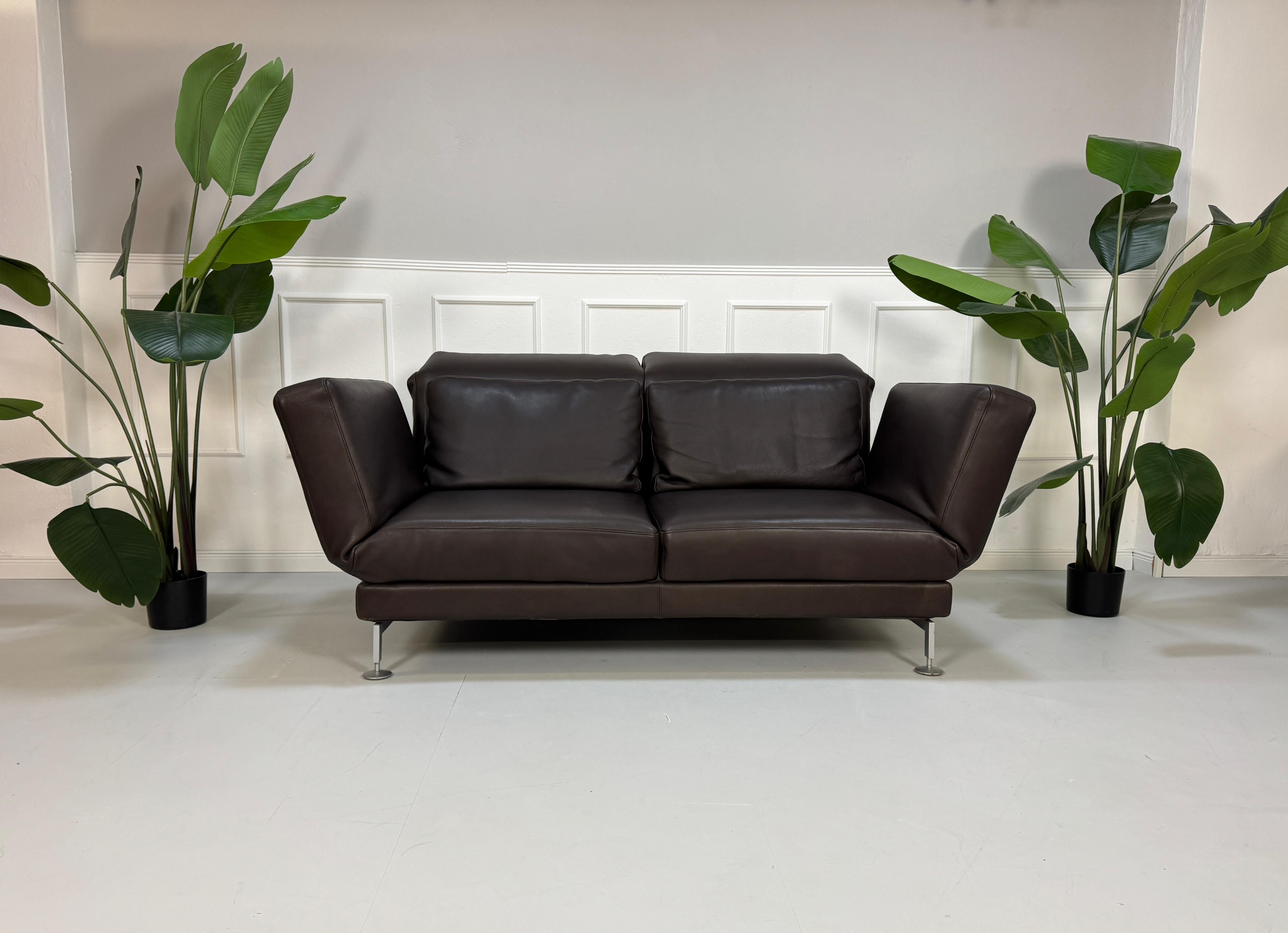 Gebrauchtes Brühl Moule 2-Sitzer Leder Sofa in der Farbe Braun vor einer Wand, stilvoll und modern eingerichtet.