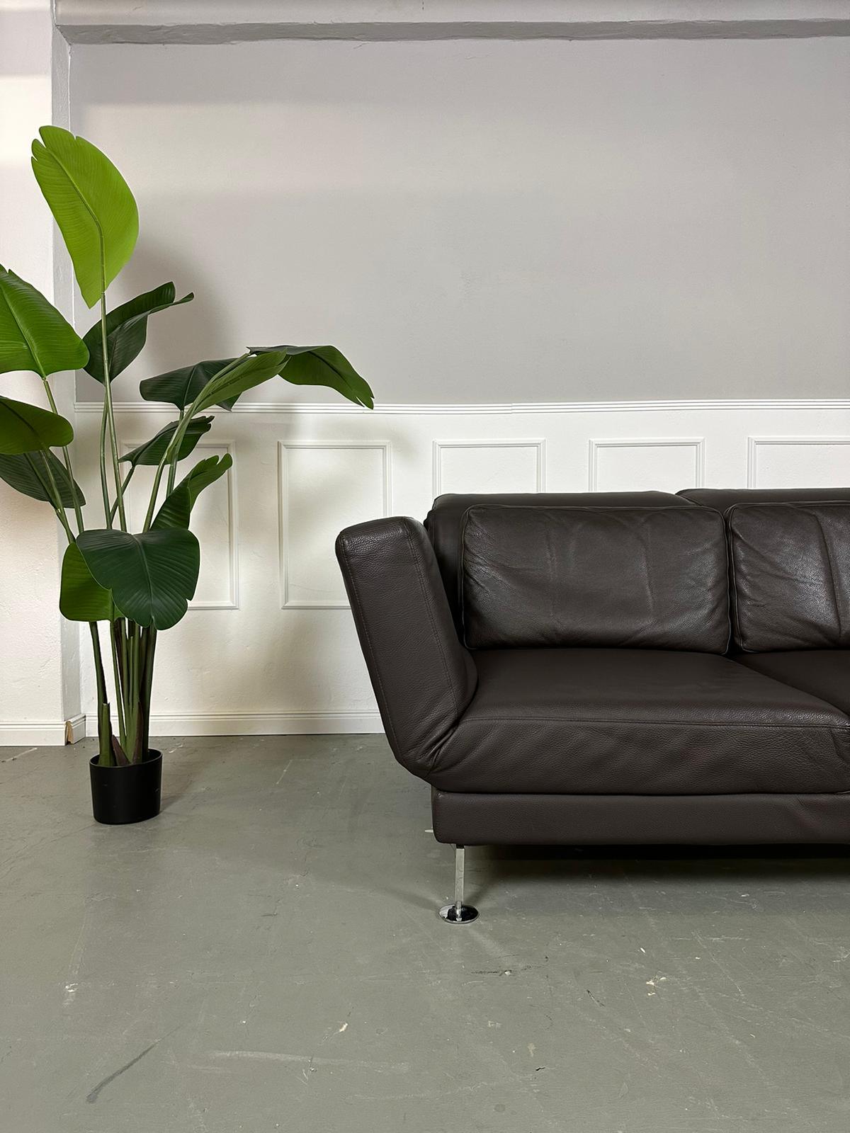 Gebrauchtes Brühl Moule 2-Sitzer Leder Sofa in der Farbe Braun vor einer Wand, stilvoll und modern eingerichtet.