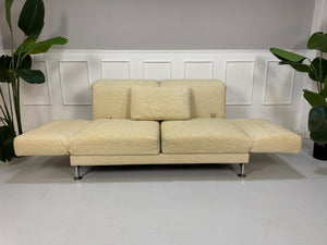 Gebrauchtes Brühl Moule Stoff Sofa in der Farbe Beige vor einer Wand, stilvoll und modern eingerichtet.