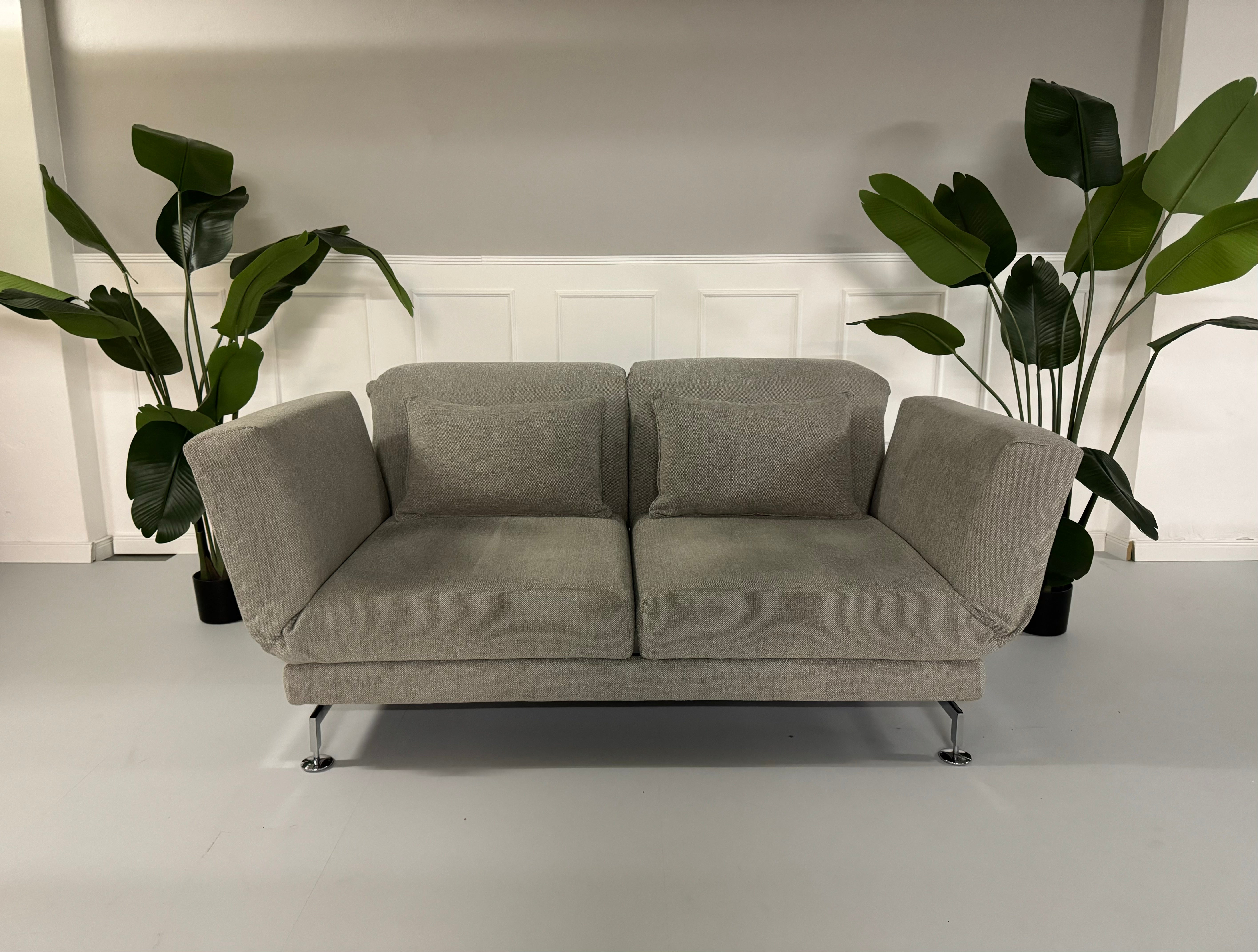 Gebrauchtes Brühl Moule 2-Sitzer Stoff Sofa in der Farbe Grau vor einer Wand, stilvoll und modern eingerichtet.