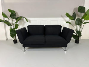 Gebrauchtes Brühl Moule 2-Sitzer Stoff Sofa in der Farbe Schwarz vor einer Wand, stilvoll und modern eingerichtet.