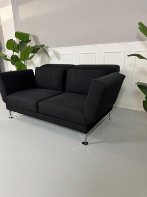 Gebrauchtes Brühl Moule 2-Sitzer Stoff Sofa in der Farbe Schwarz vor einer Wand, stilvoll und modern eingerichtet.