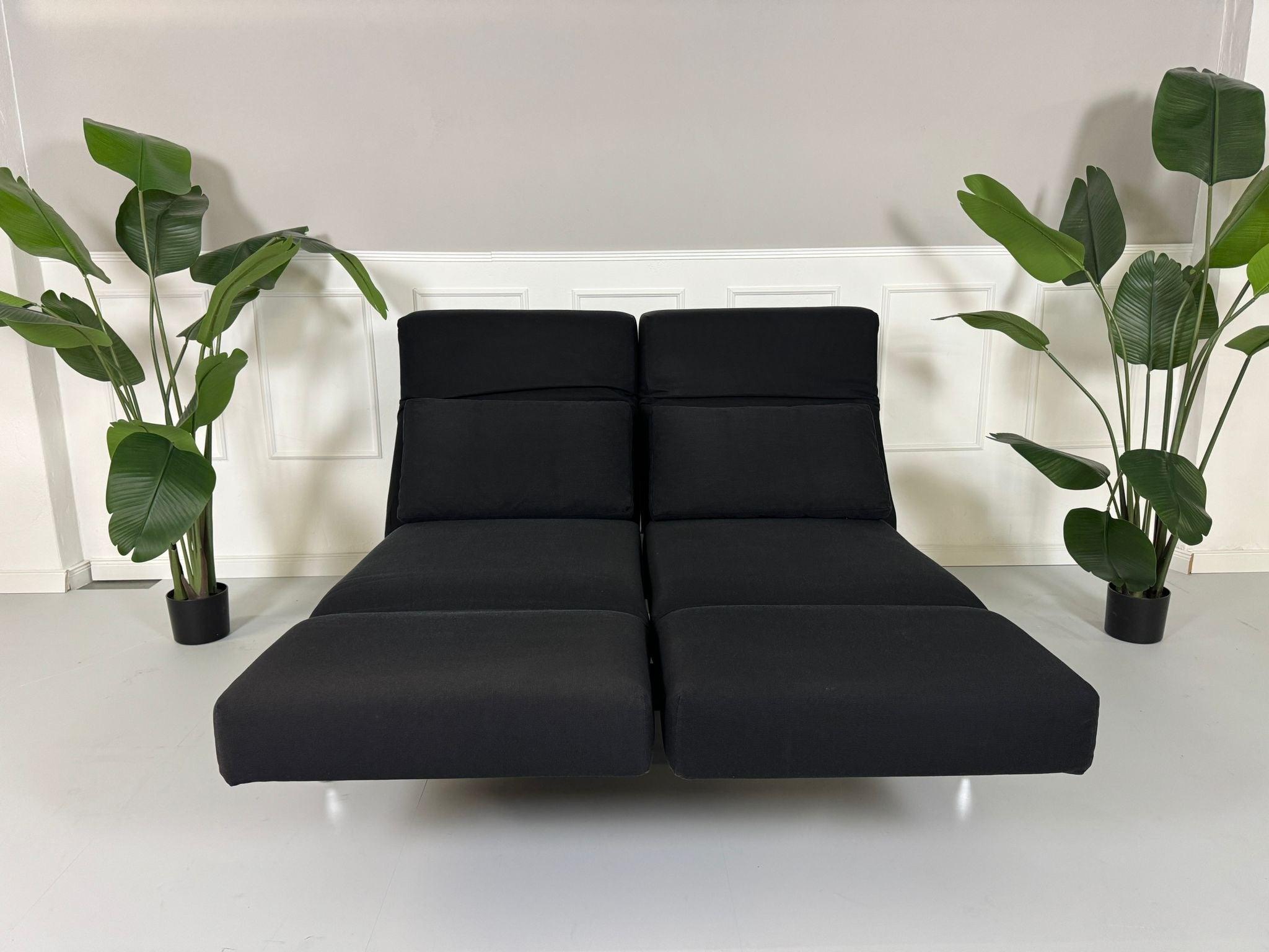 Gebrauchtes Brühl Moule 2-Sitzer Stoff Sofa in der Farbe Schwarz vor einer Wand, stilvoll und modern eingerichtet.