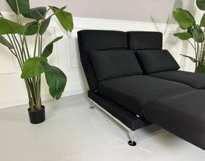 Gebrauchtes Brühl Moule 2-Sitzer Stoff Sofa in der Farbe Schwarz vor einer Wand, stilvoll und modern eingerichtet.