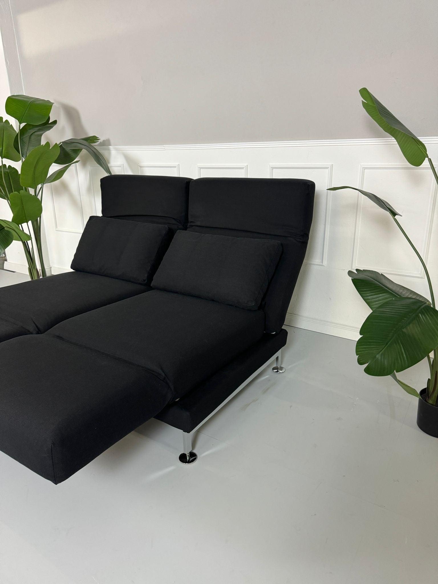 Gebrauchtes Brühl Moule 2-Sitzer Stoff Sofa in der Farbe Schwarz vor einer Wand, stilvoll und modern eingerichtet.