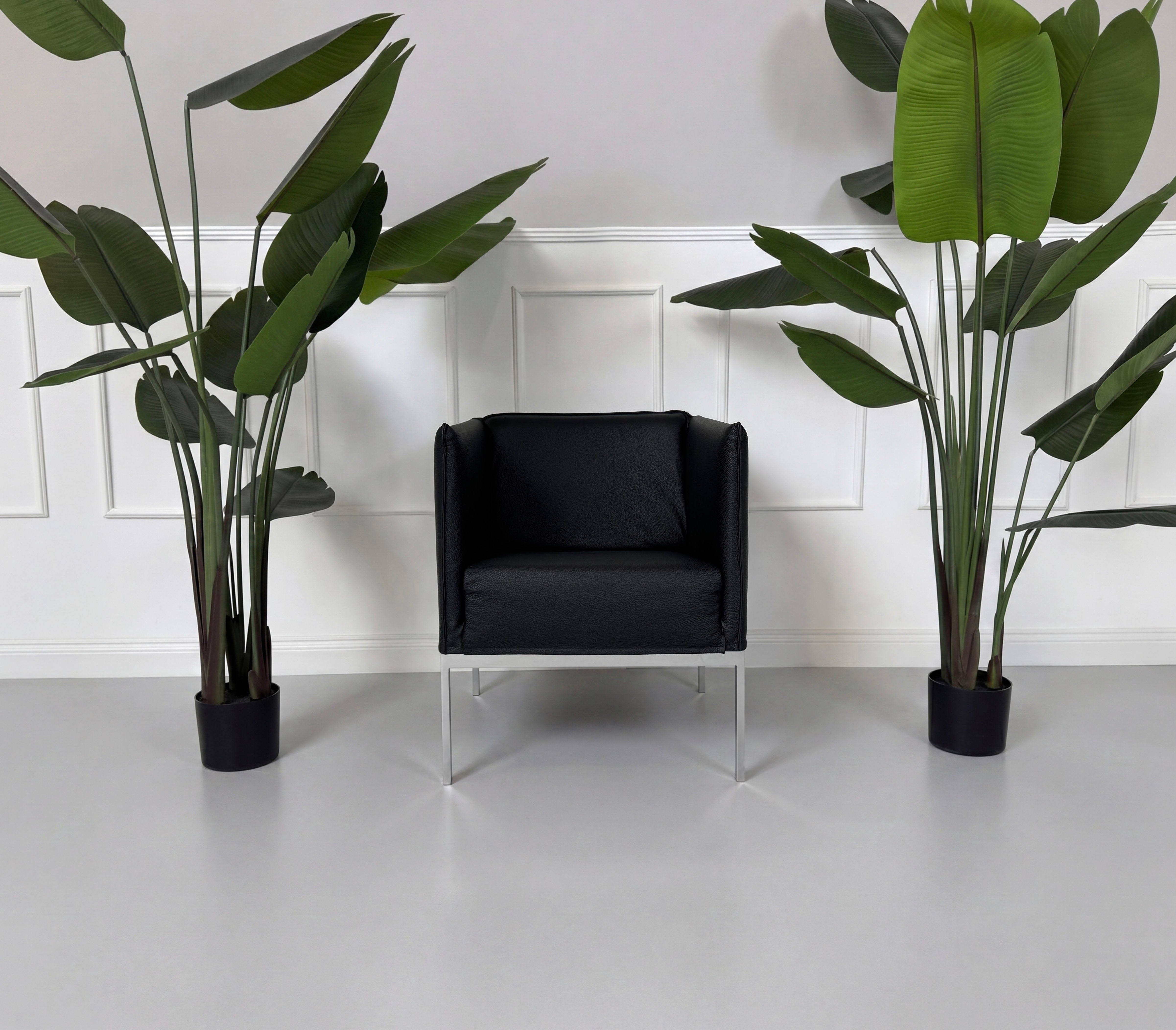 Gebrauchter schwarzer Brühl Randolph Designer Leder Sessel vor einer Wand, stilvoll und modern eingerichtet.