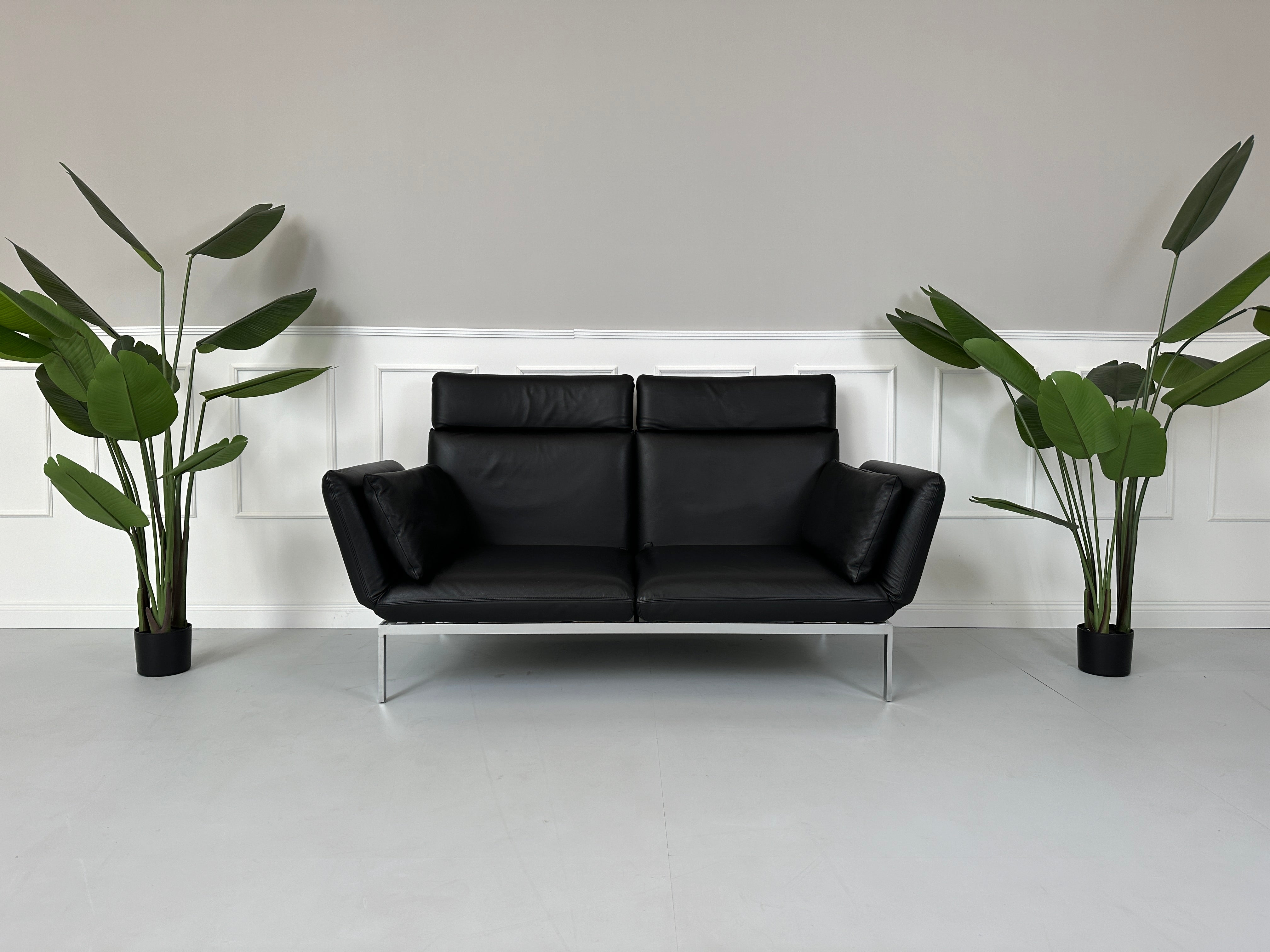 Gebrauchtes Brühl Roro Leder Sofa in der Farbe Schwarz vor einer Wand, stilvoll und modern eingerichtet.