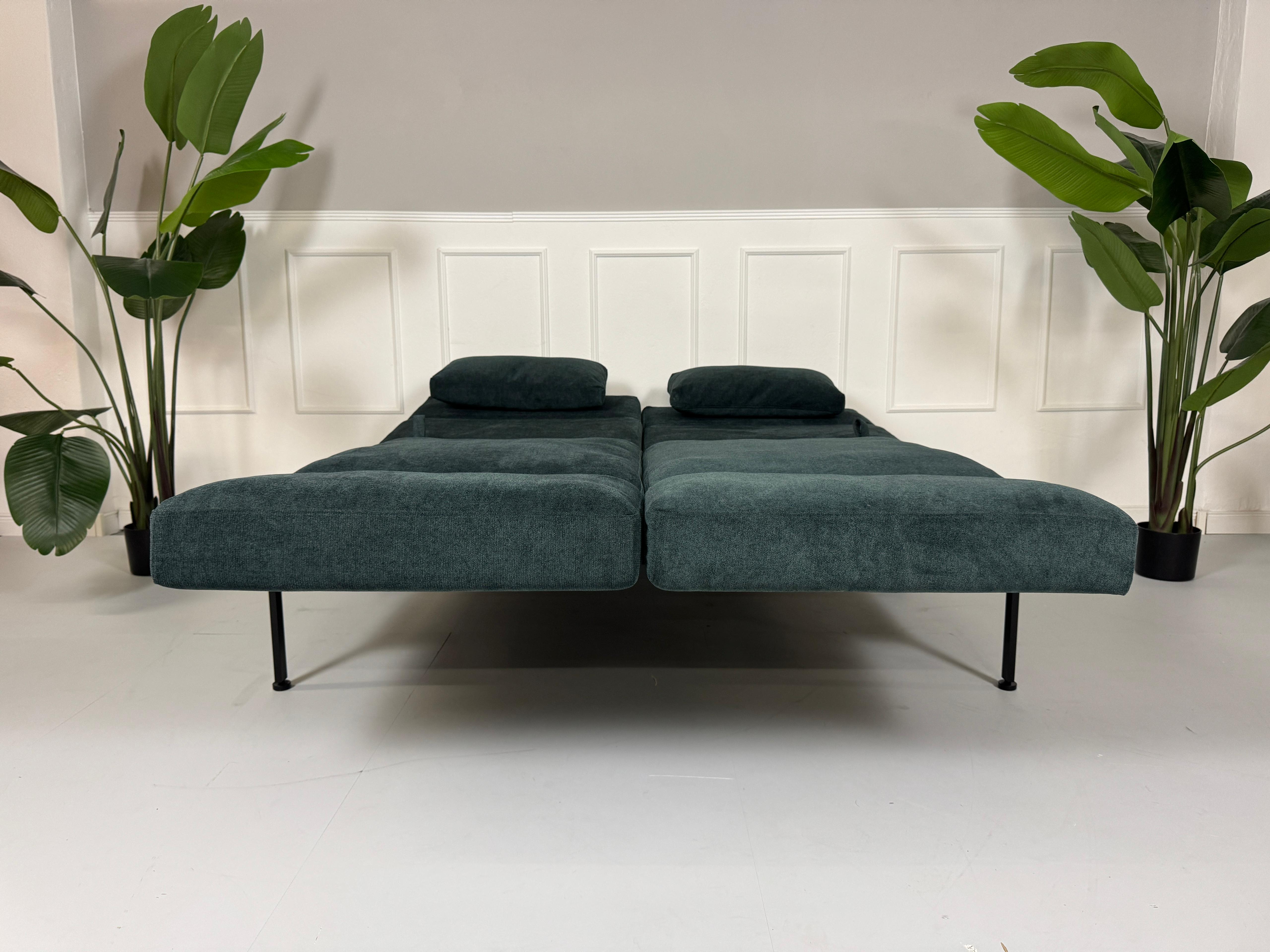 Gebrauchtes Brühl Roro Soft Stoff Sofa in der Farbe Blau vor einer Wand, stilvoll und modern eingerichtet.