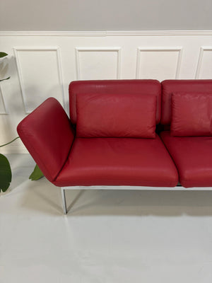 Gebrauchtes rotes Brühl Roro Designer Leder Sofa vor einer Wand, stilvoll und modern eingerichtet.