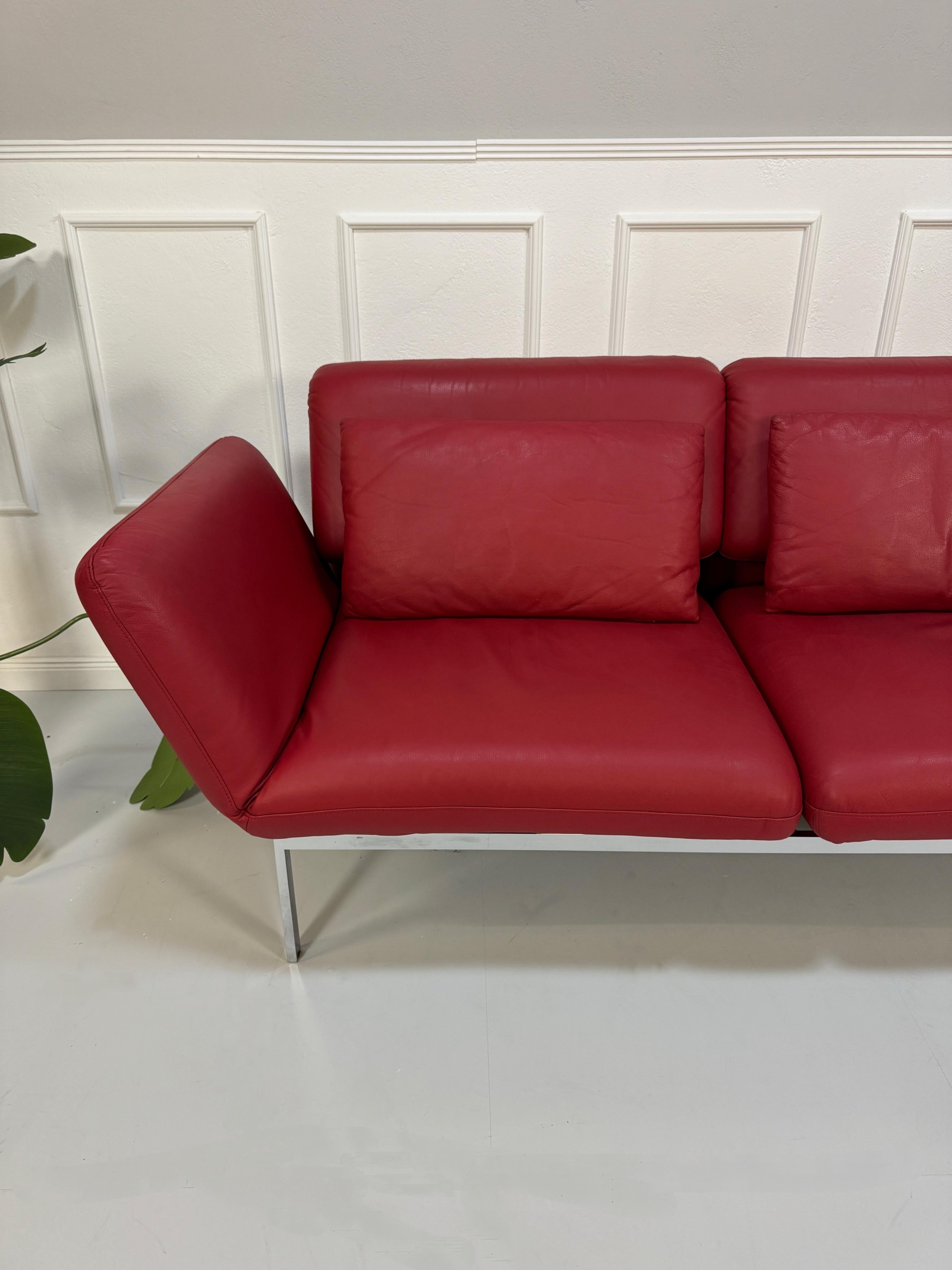 Gebrauchtes rotes Brühl Roro Designer Leder Sofa vor einer Wand, stilvoll und modern eingerichtet.