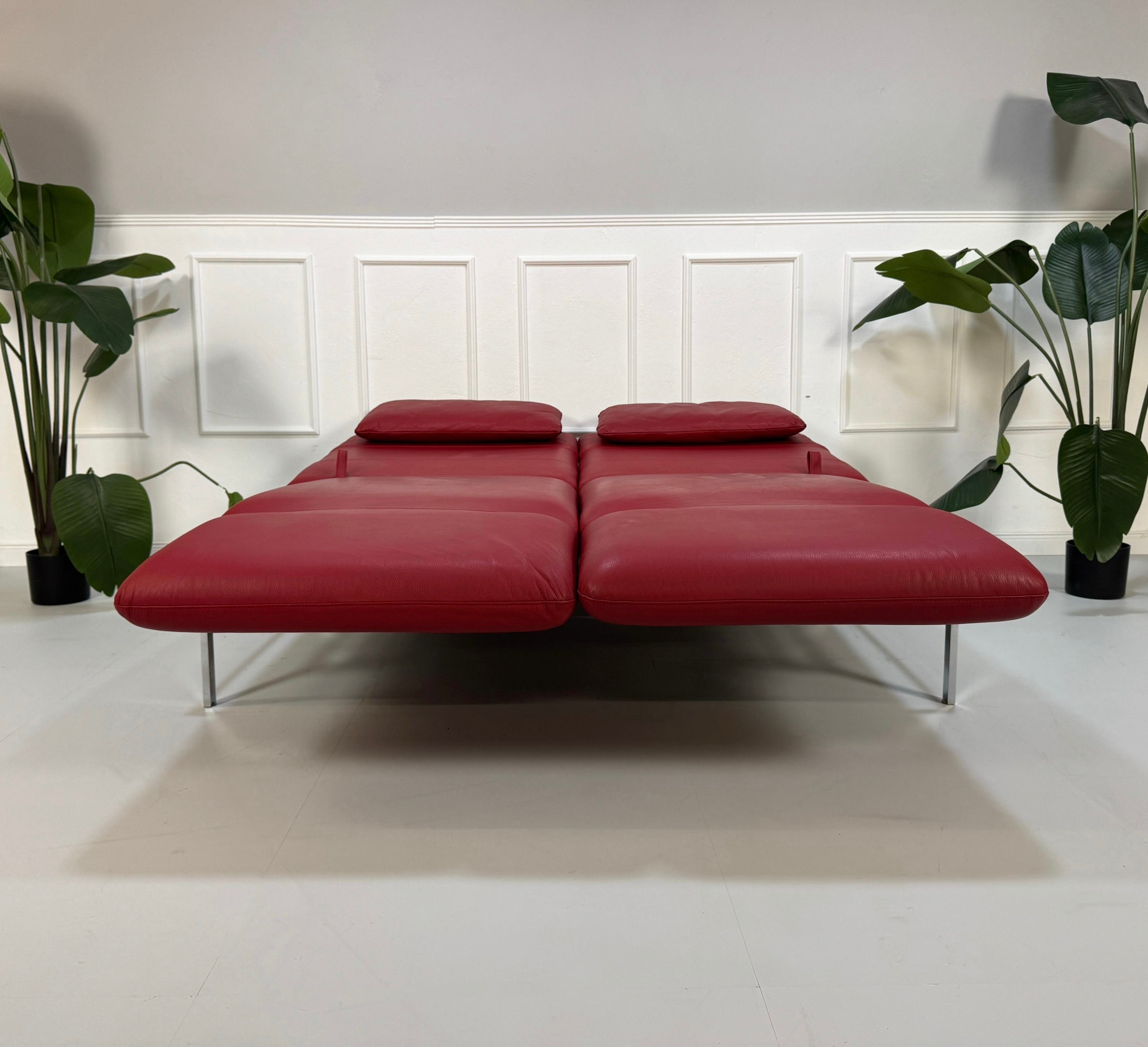Gebrauchtes rotes Brühl Roro Designer Leder Sofa vor einer Wand, stilvoll und modern eingerichtet.