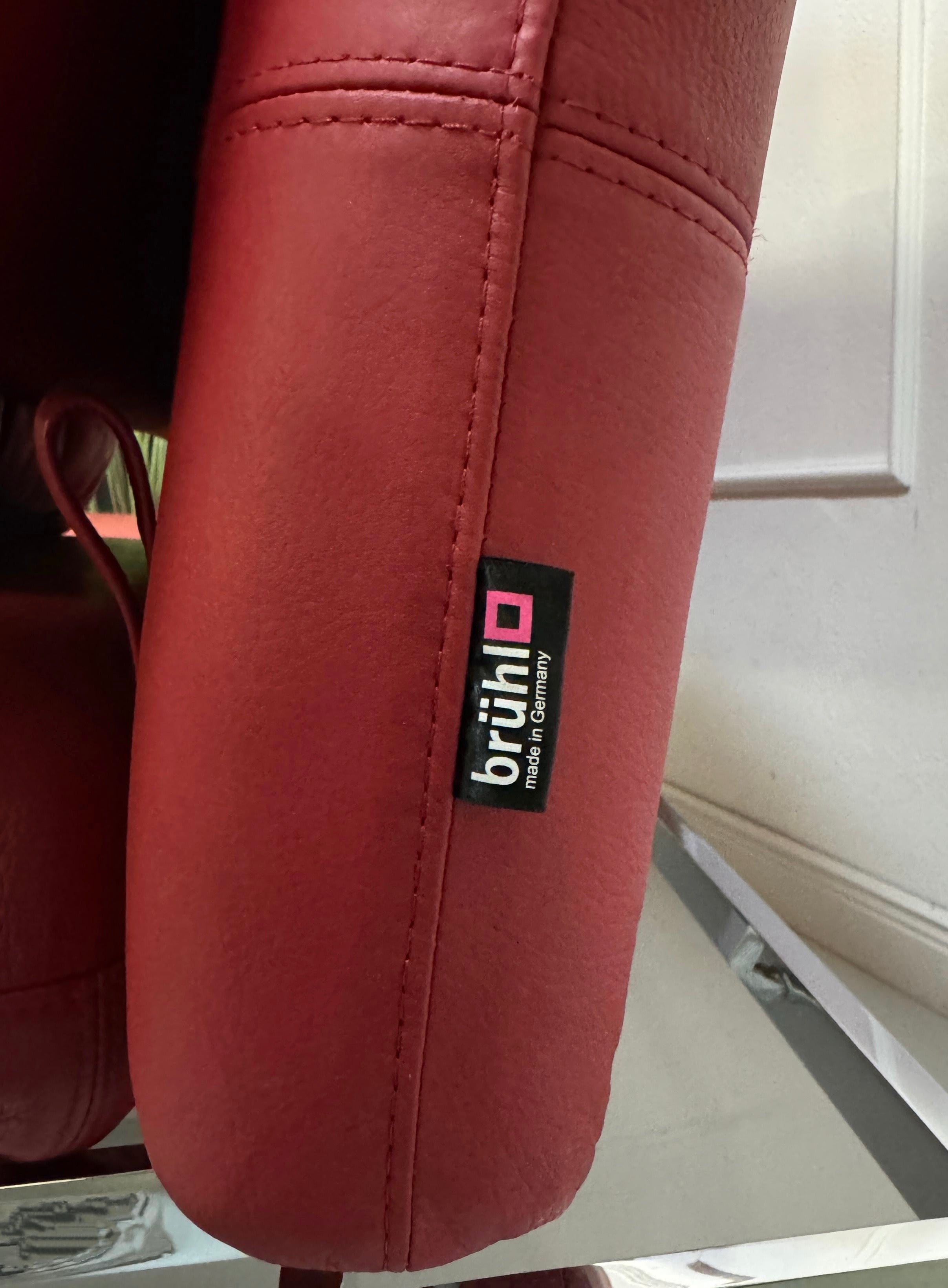 Gebrauchtes rotes Brühl Roro Designer Leder Sofa vor einer Wand, stilvoll und modern eingerichtet.