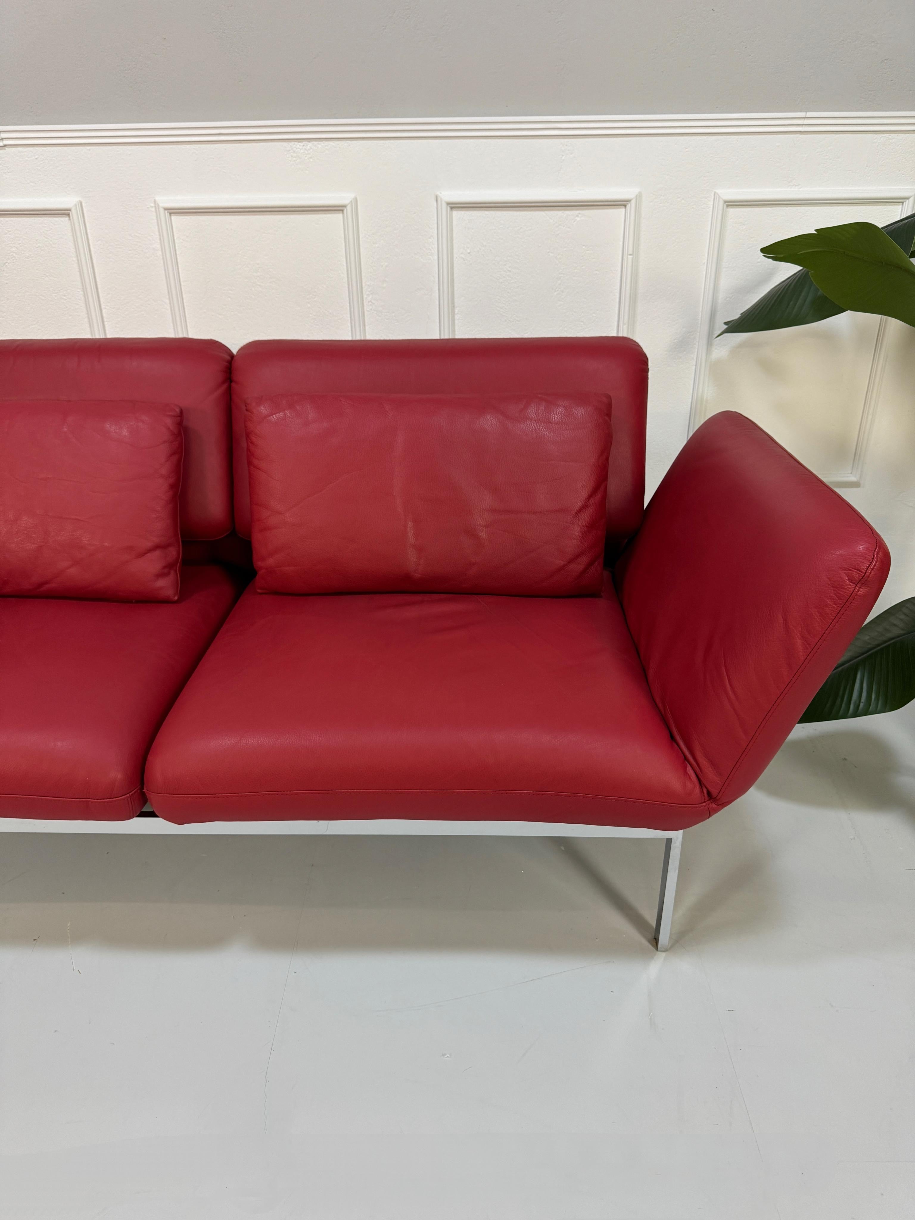 Gebrauchtes rotes Brühl Roro Designer Leder Sofa vor einer Wand, stilvoll und modern eingerichtet.