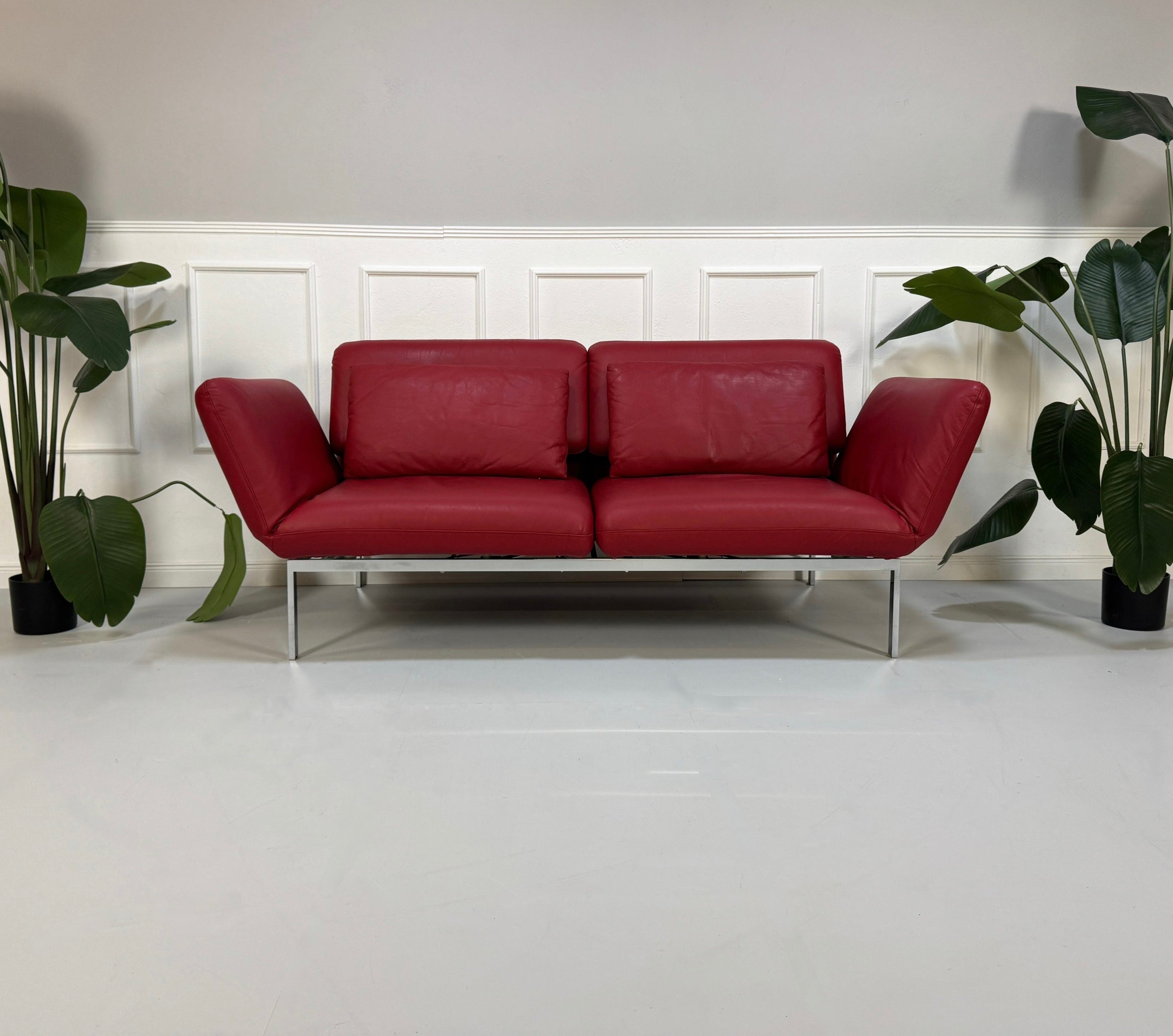 Gebrauchtes rotes Brühl Roro Designer Leder Sofa vor einer Wand, stilvoll und modern eingerichtet.