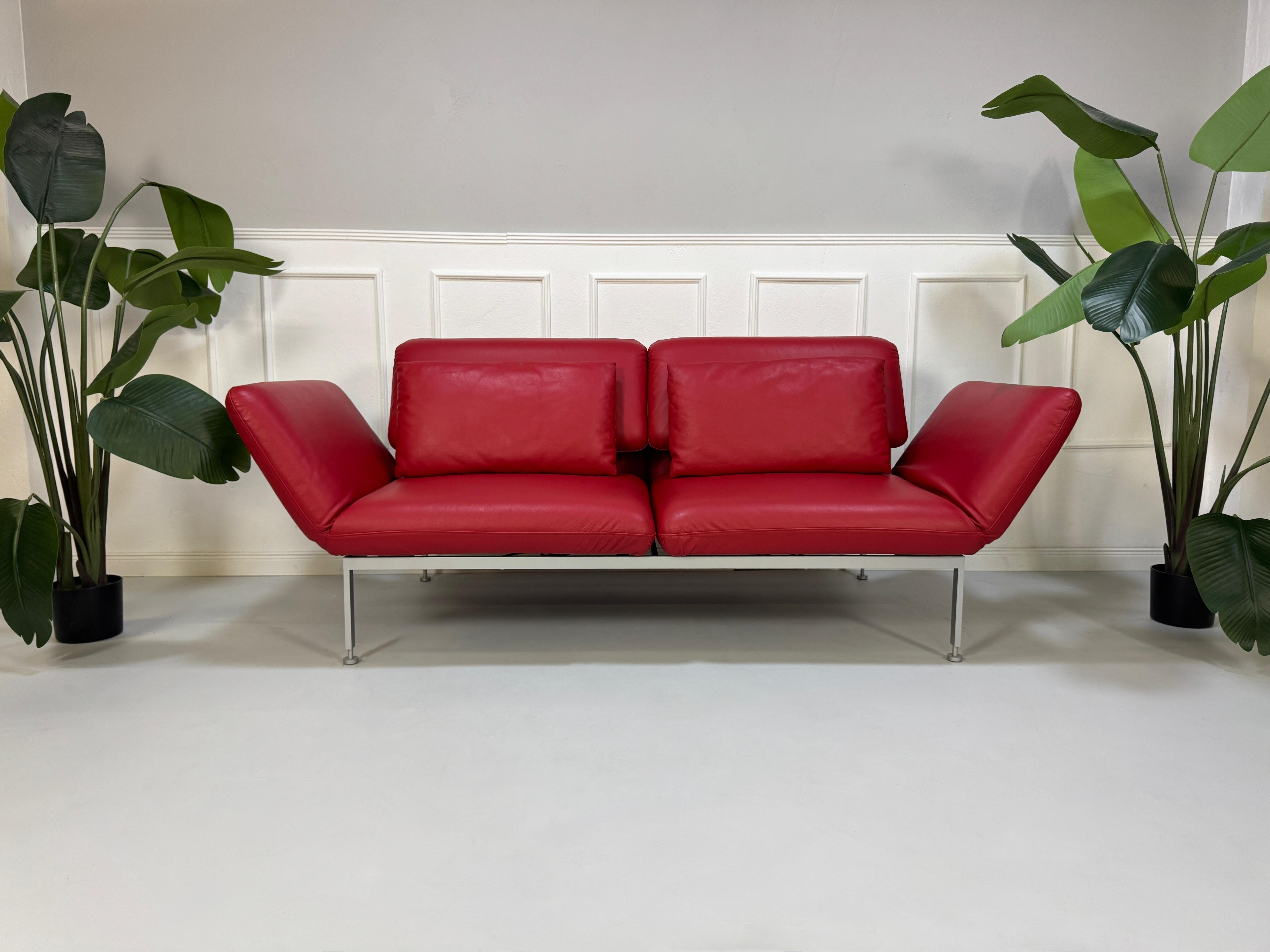 Ausstellungsstück Brühl Roro Designer Leder Sofa in der Farbe Rot vor einer Wand, stilvoll und modern eingerichtet.