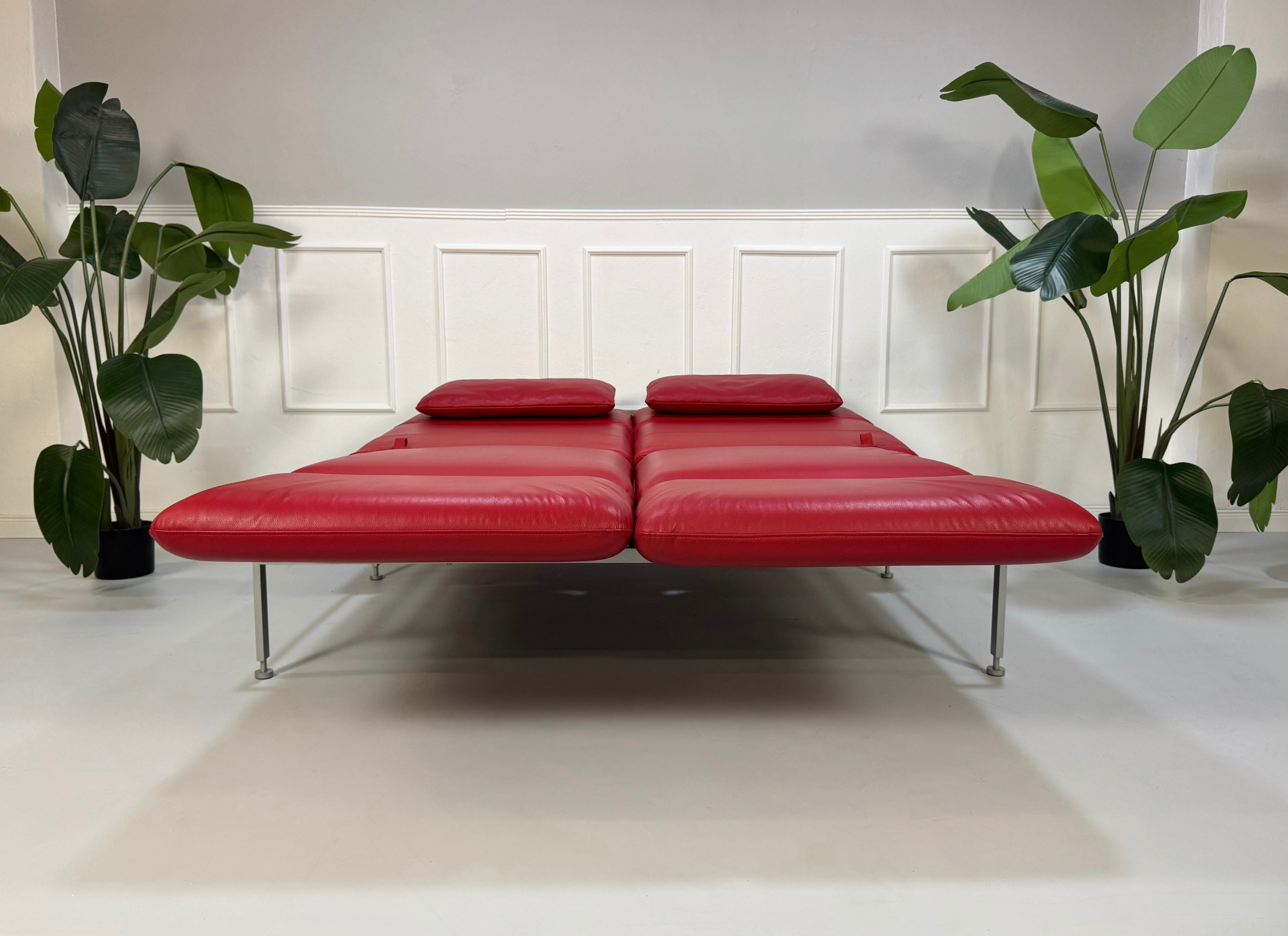 Ausstellungsstück Brühl Roro Designer Leder Sofa in der Farbe Rot vor einer Wand, stilvoll und modern eingerichtet.