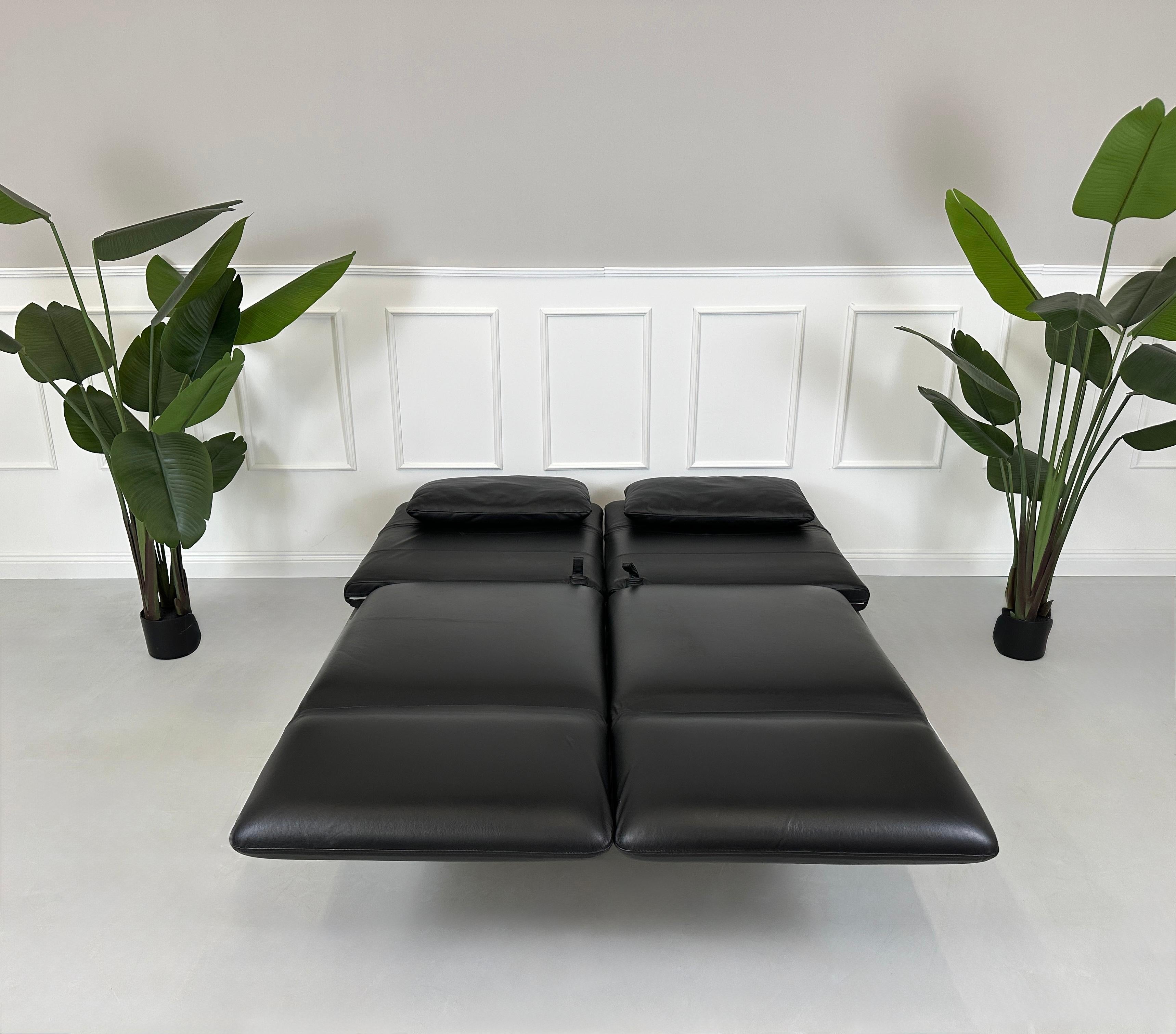 Gebrauchtes schwarzes Brühl Roro Designer Leder Sofa vor einer Wand, stilvoll und modern eingerichtet.