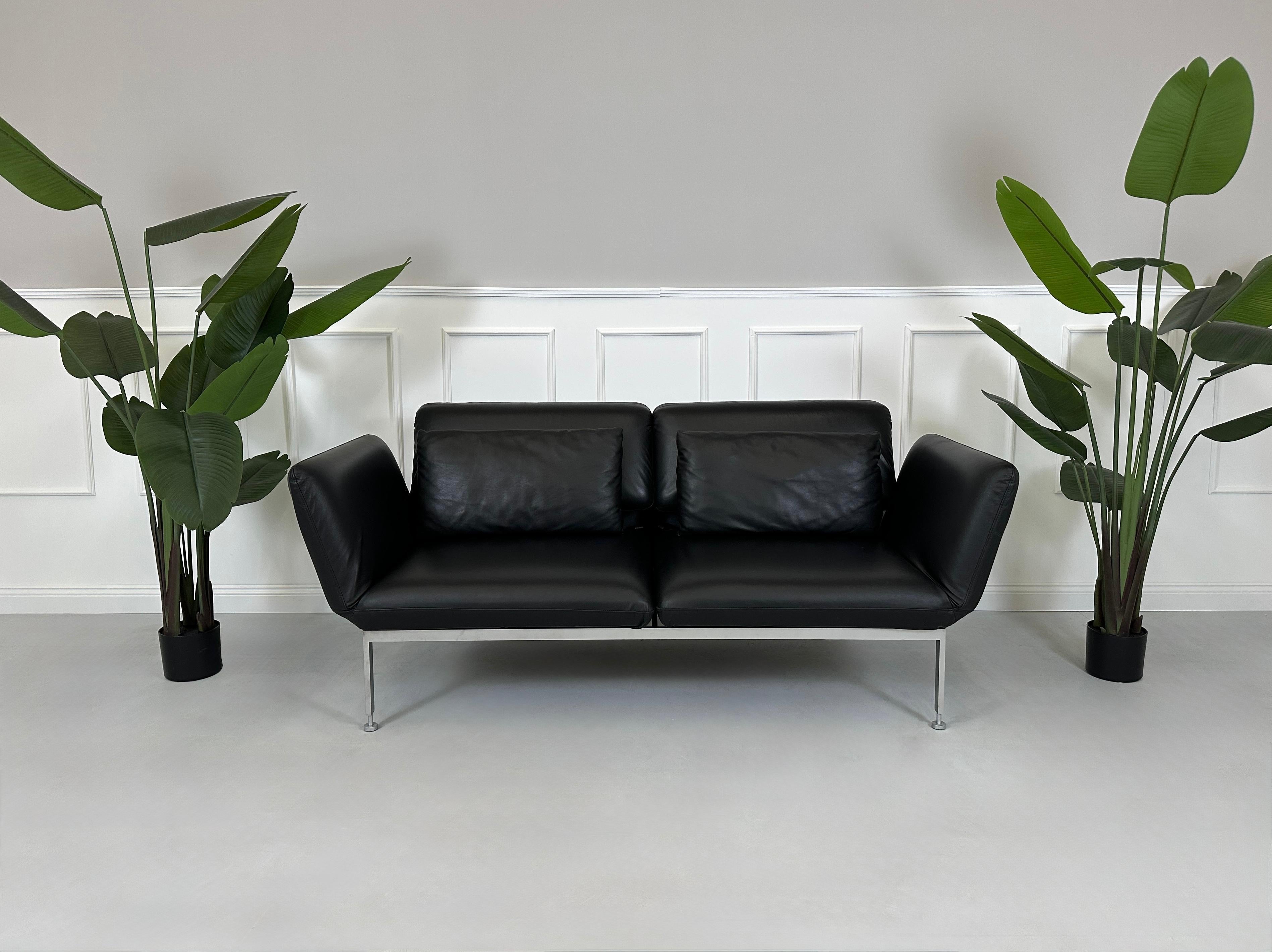 Gebrauchtes schwarzes Brühl Roro Designer Leder Sofa vor einer Wand, stilvoll und modern eingerichtet.