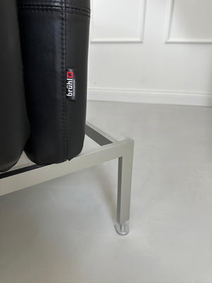 Gebrauchtes schwarzes Brühl Roro Designer Leder Sofa vor einer Wand, stilvoll und modern eingerichtet.