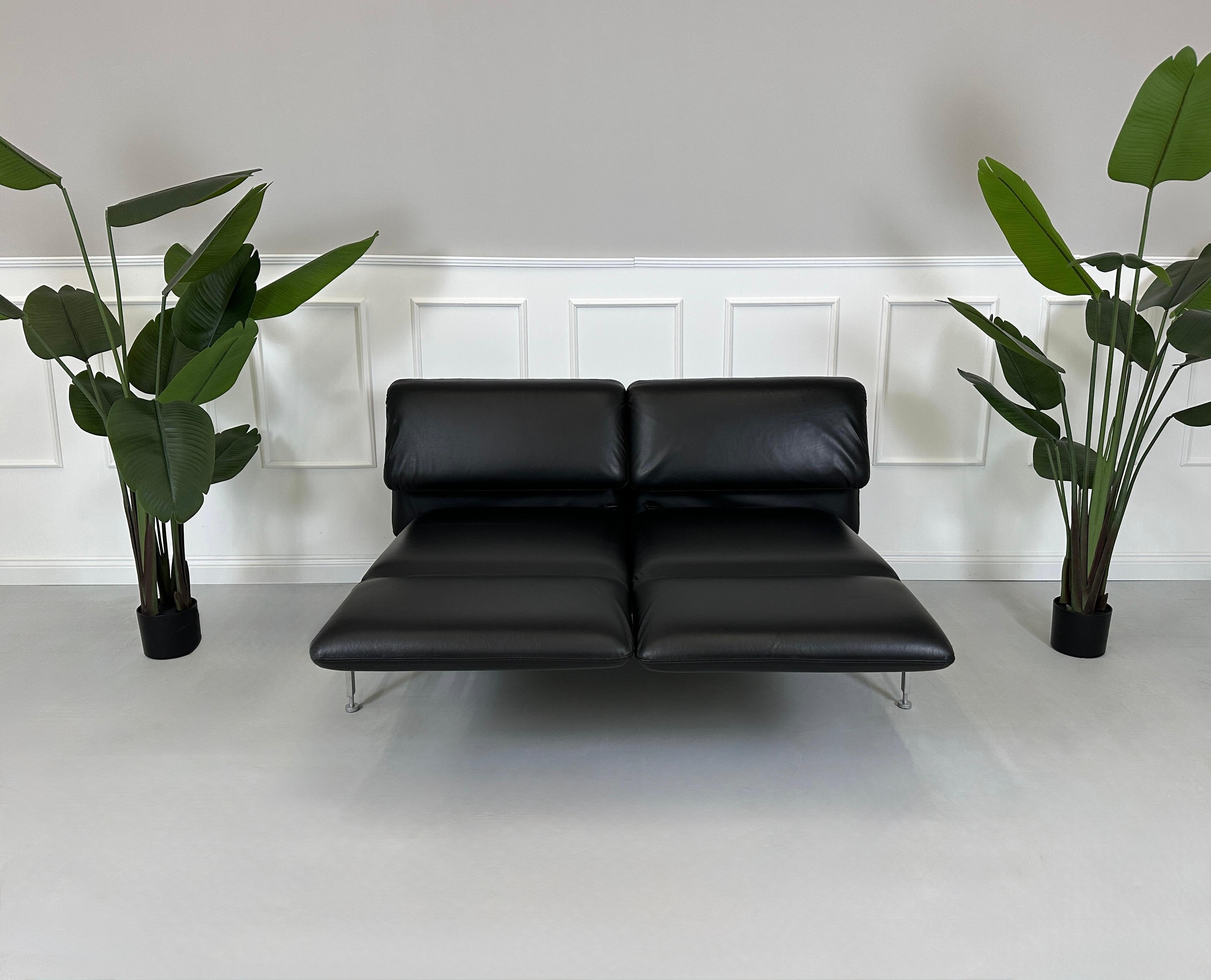 Gebrauchtes schwarzes Brühl Roro Designer Leder Sofa vor einer Wand, stilvoll und modern eingerichtet.