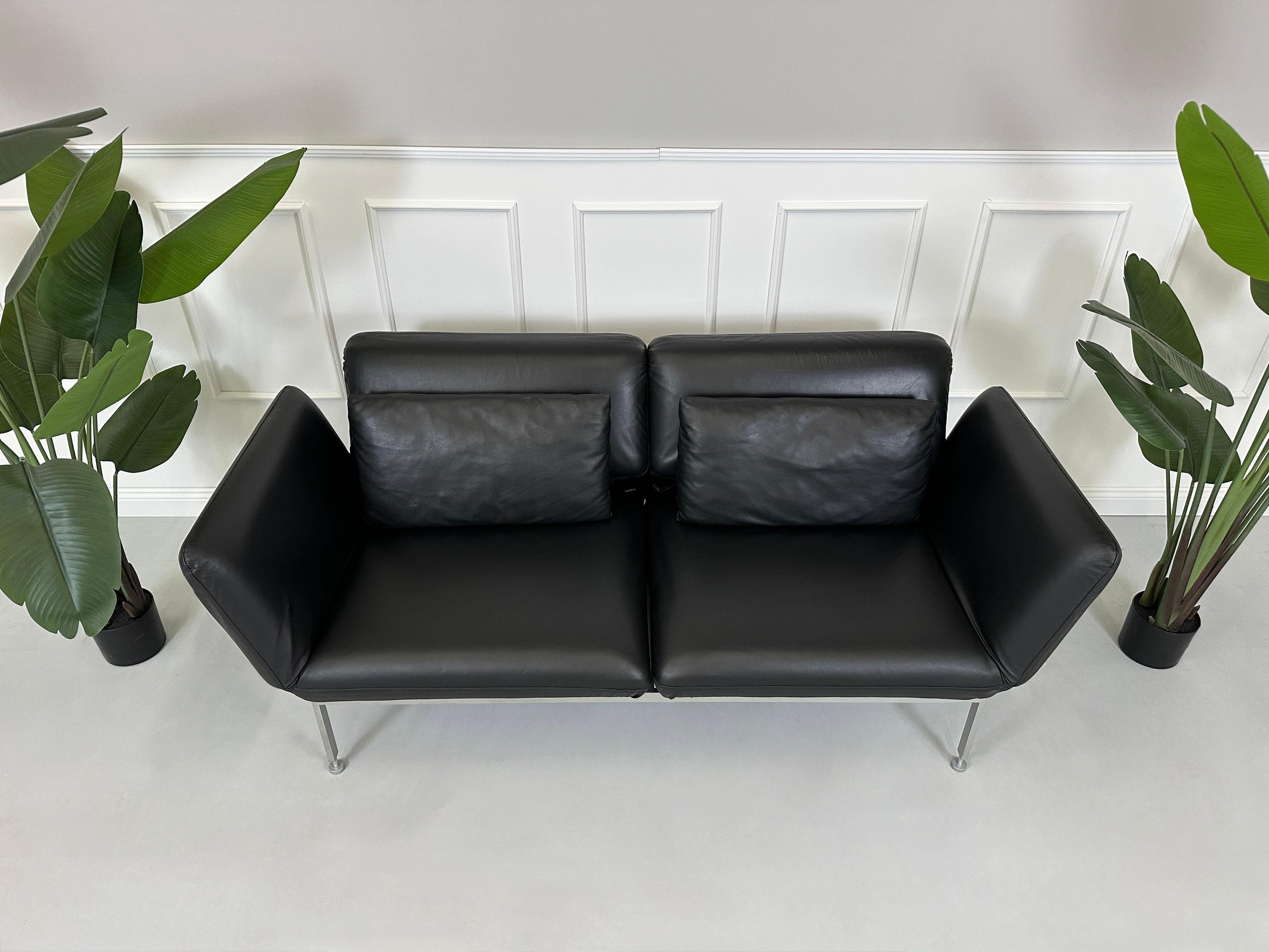 Gebrauchtes schwarzes Brühl Roro Designer Leder Sofa vor einer Wand, stilvoll und modern eingerichtet.