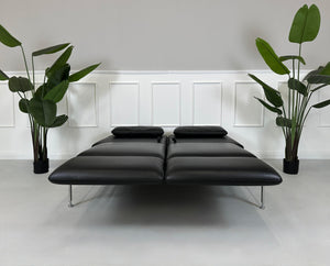 Gebrauchtes schwarzes Brühl Roro Designer Leder Sofa vor einer Wand, stilvoll und modern eingerichtet.