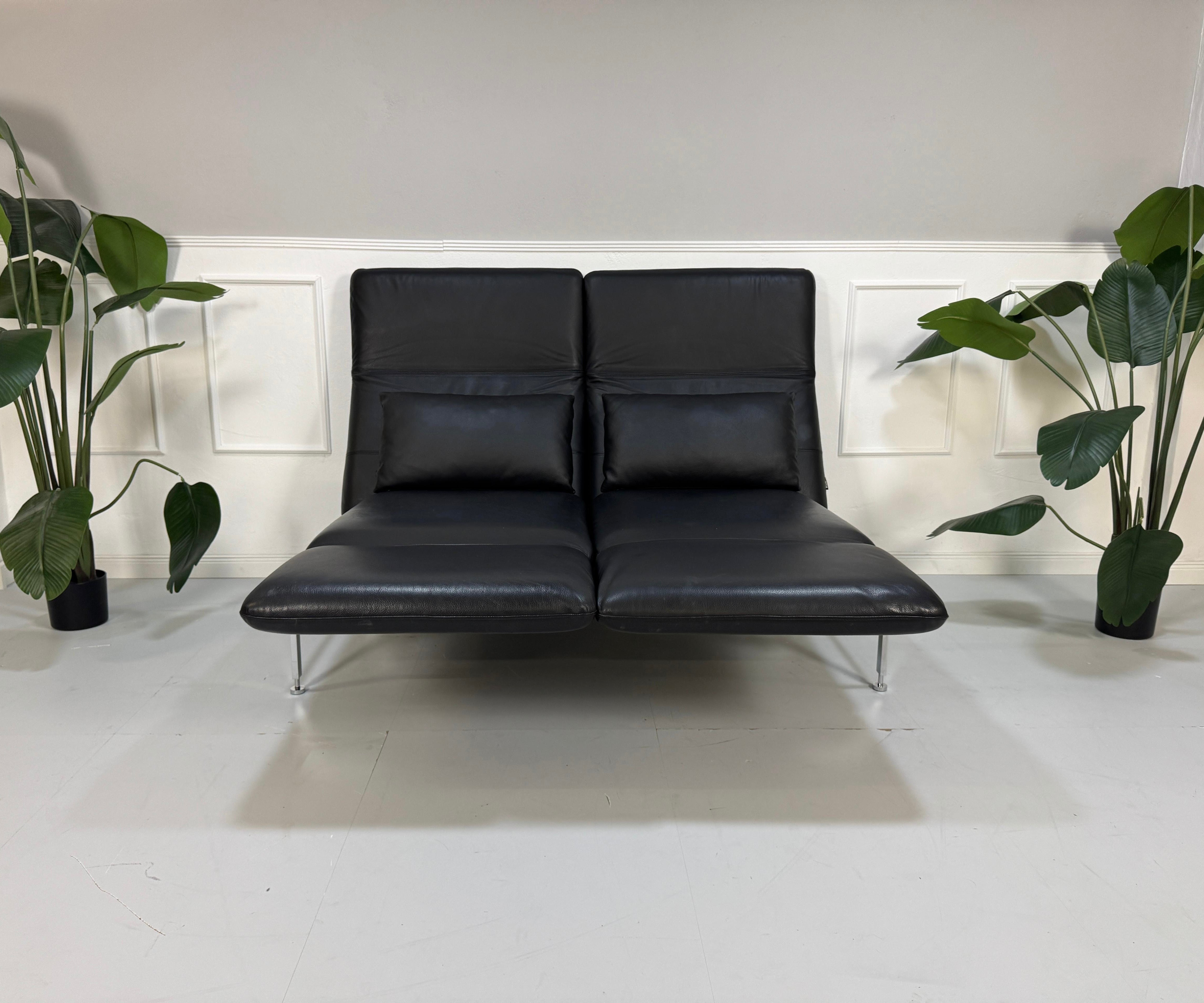 Gebrauchtes schwarzes Brühl Roro Designer Leder Ausstellungsstück Sofa vor einer Wand, stilvoll und modern eingerichtet.