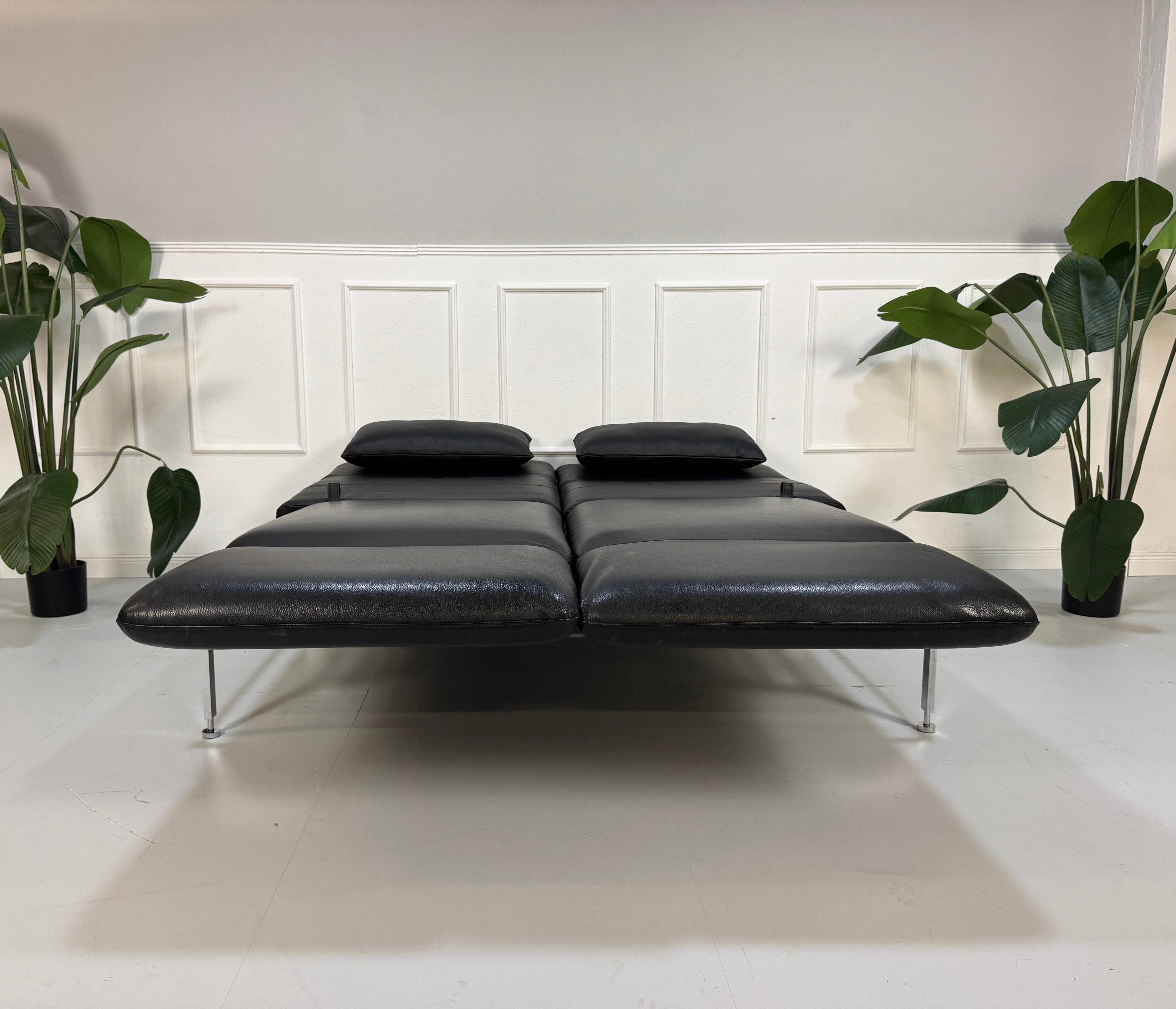 Gebrauchtes schwarzes Brühl Roro Designer Leder Ausstellungsstück Sofa vor einer Wand, stilvoll und modern eingerichtet.