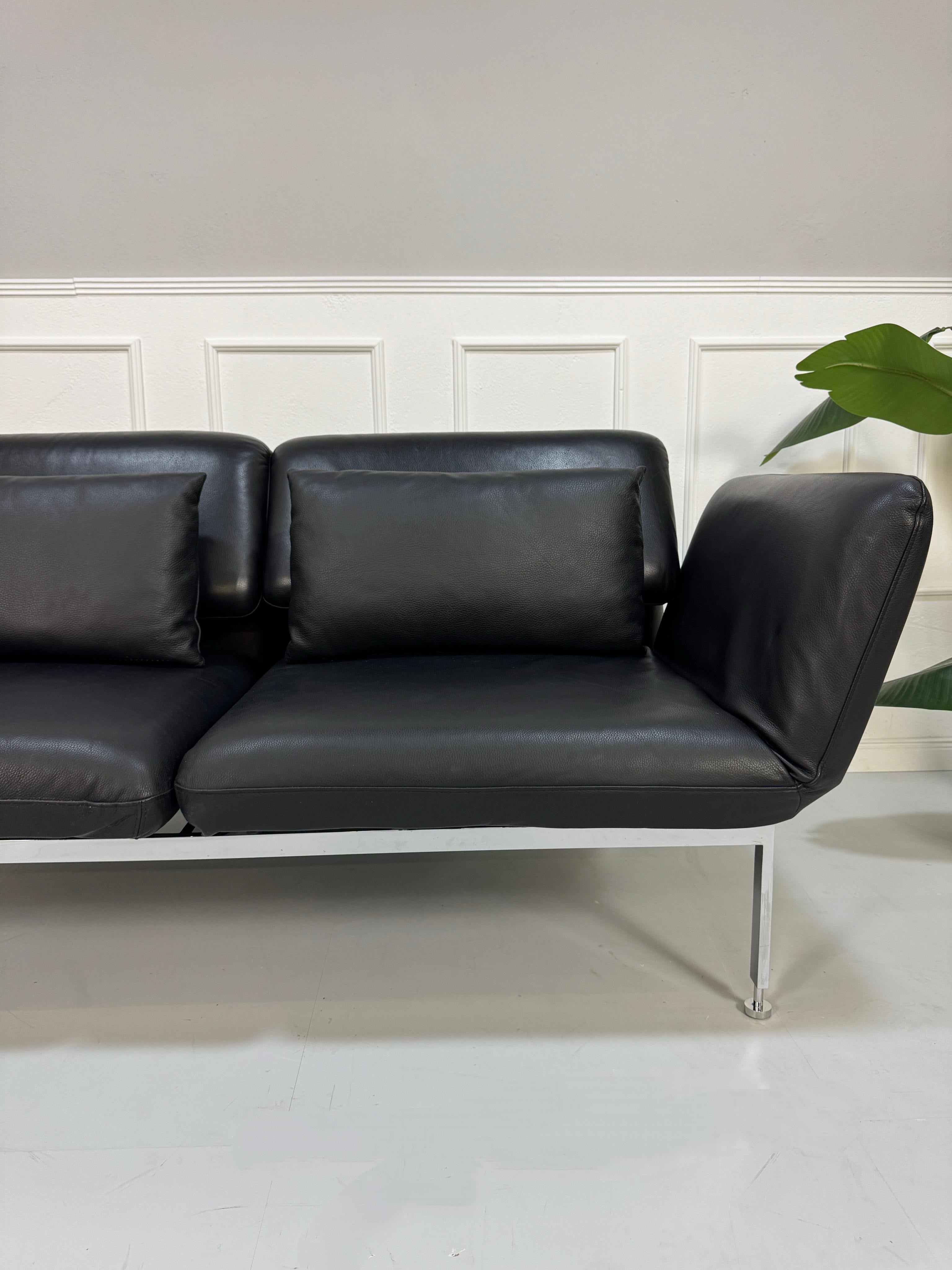 Gebrauchtes schwarzes Brühl Roro Designer Leder Ausstellungsstück Sofa vor einer Wand, stilvoll und modern eingerichtet.