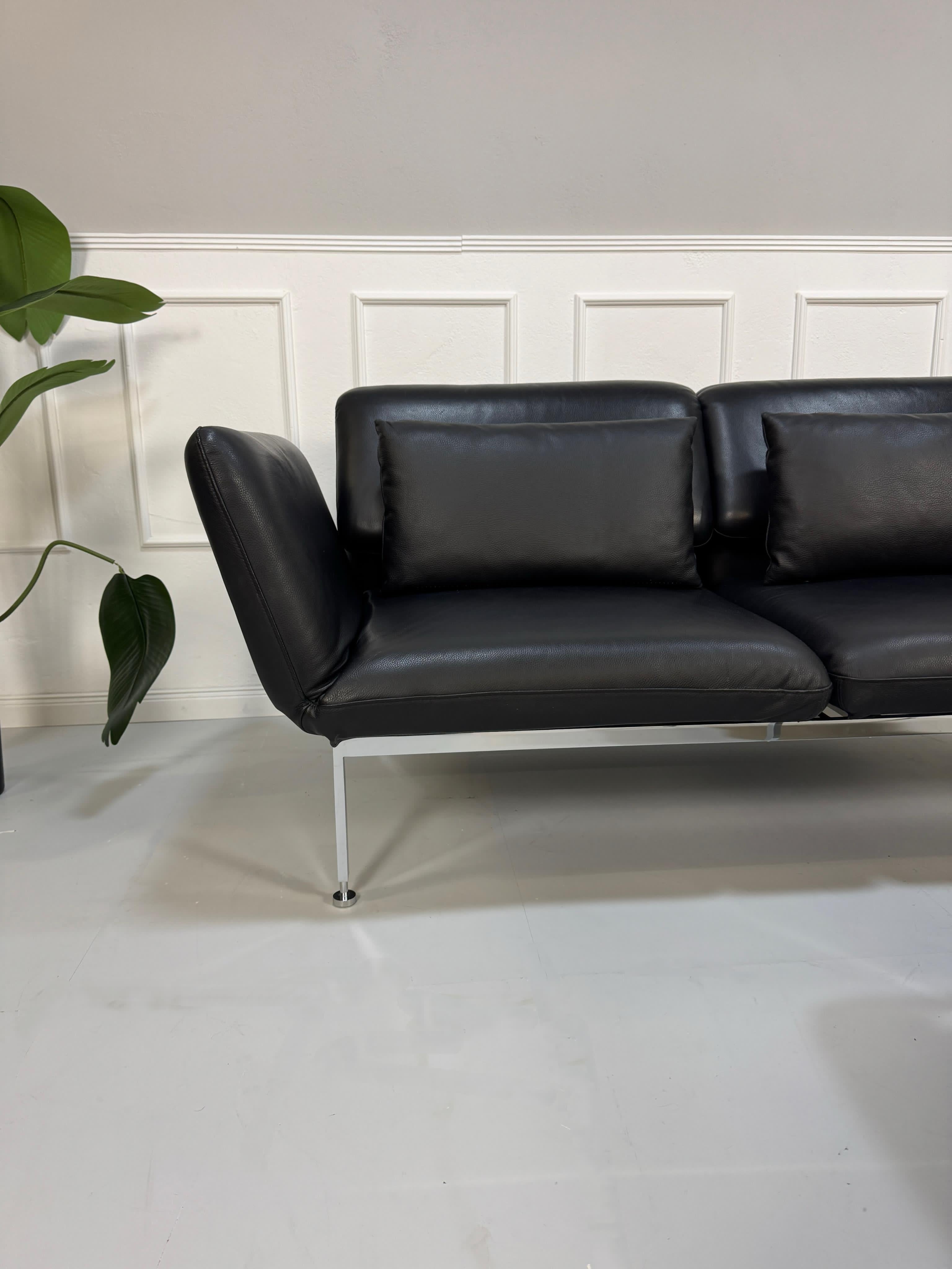 Gebrauchtes schwarzes Brühl Roro Designer Leder Ausstellungsstück Sofa vor einer Wand, stilvoll und modern eingerichtet.