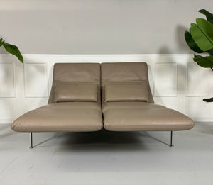 Gebrauchtes Brühl Roro Leder Sofa in der Farbe Schlamm vor einer Wand, stilvoll und modern eingerichtet.