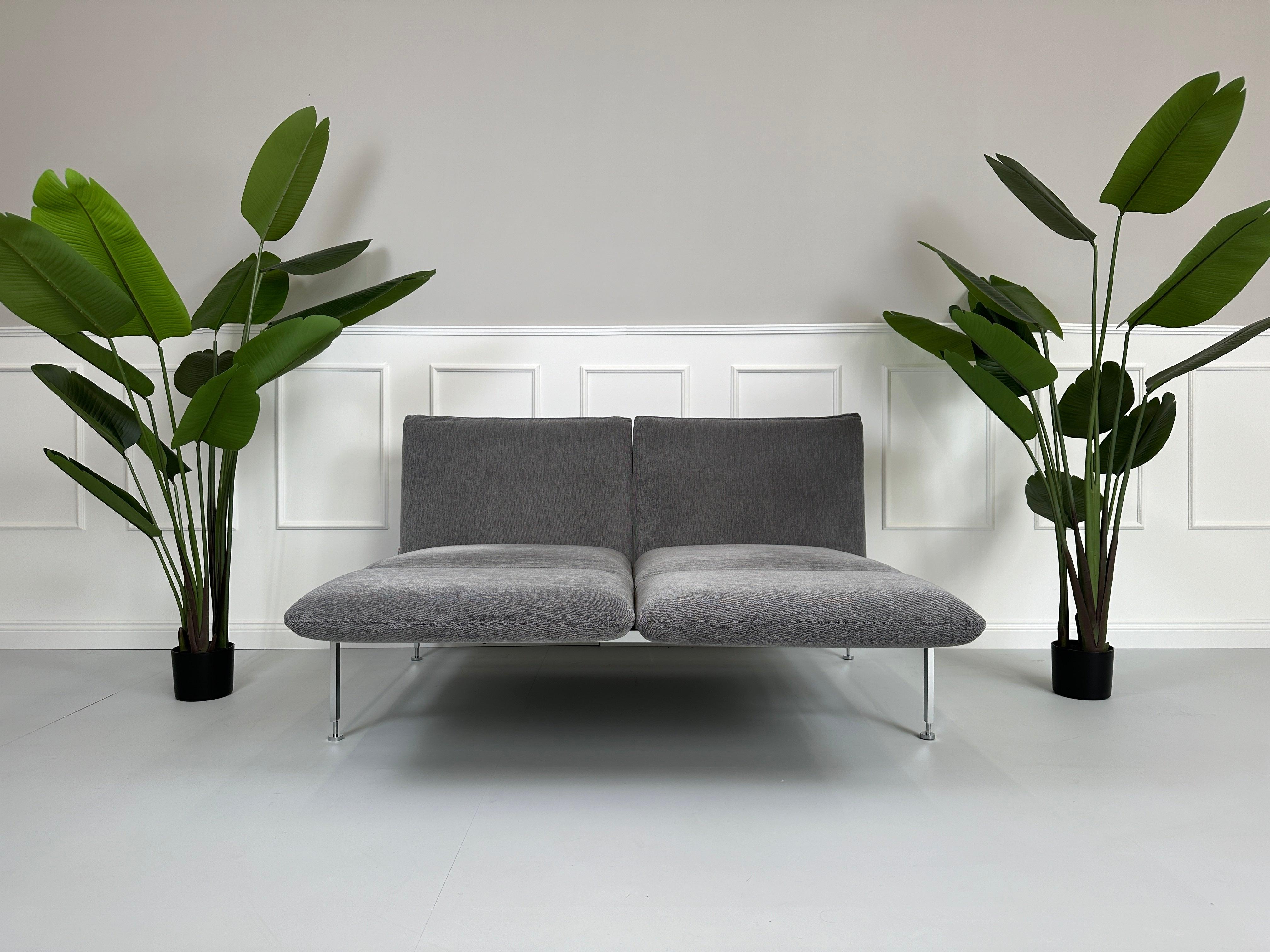 Gebrauchtes Brühl Roro Stoff Sofa in der Farbe Grau vor einer Wand, stilvoll und modern eingerichtet.