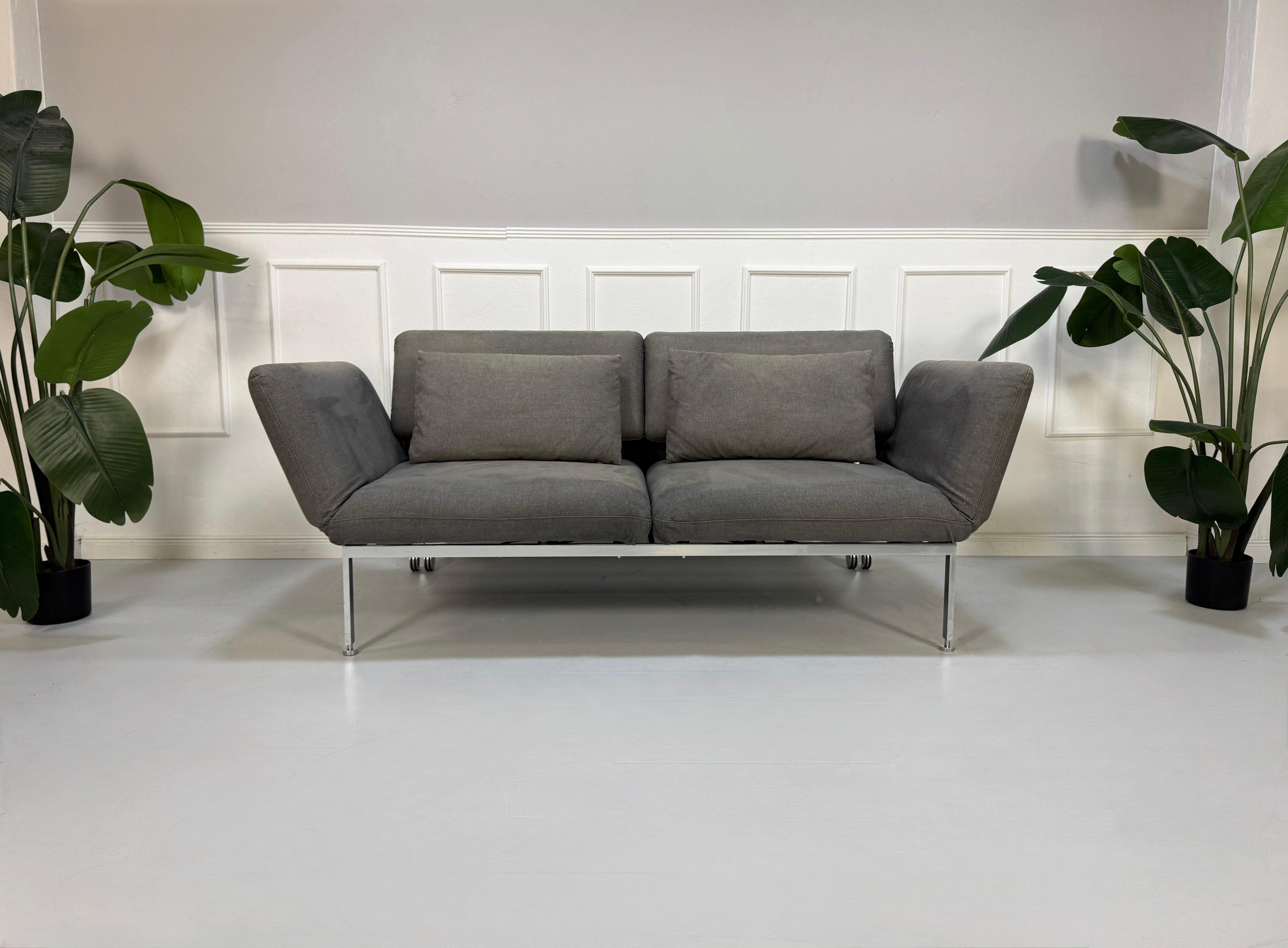 Gebrauchtes graues Brühl Roro Designer Stoff Sofa vor einer Wand, stilvoll und modern eingerichtet.