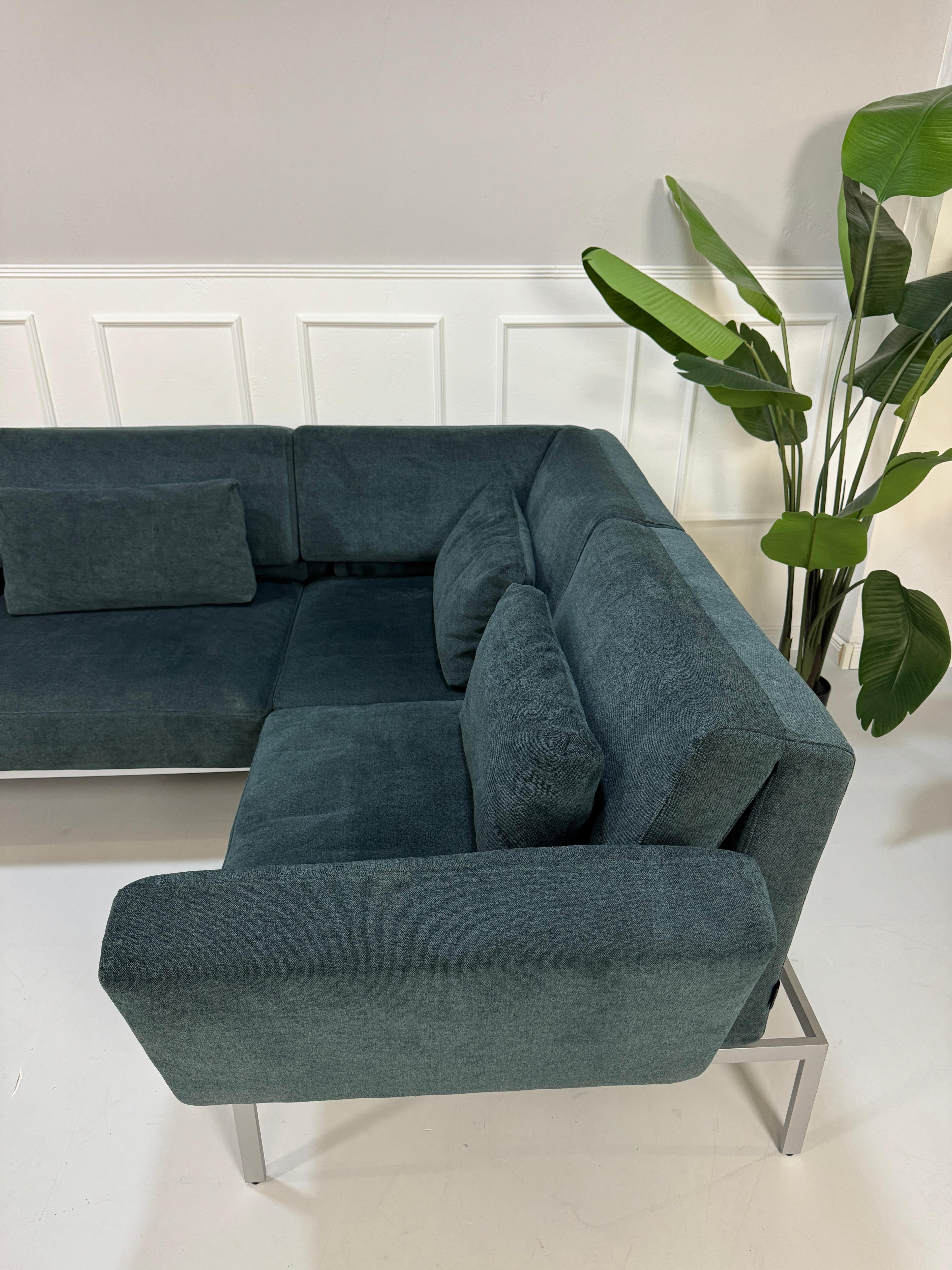 Gebrauchtes Brühl Roro Soft Stoff Ecksofa in der Farbe Blau vor einer Wand, stilvoll und modern eingerichtet.