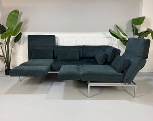 Gebrauchtes Brühl Roro Soft Stoff Ecksofa in der Farbe Blau vor einer Wand, stilvoll und modern eingerichtet.