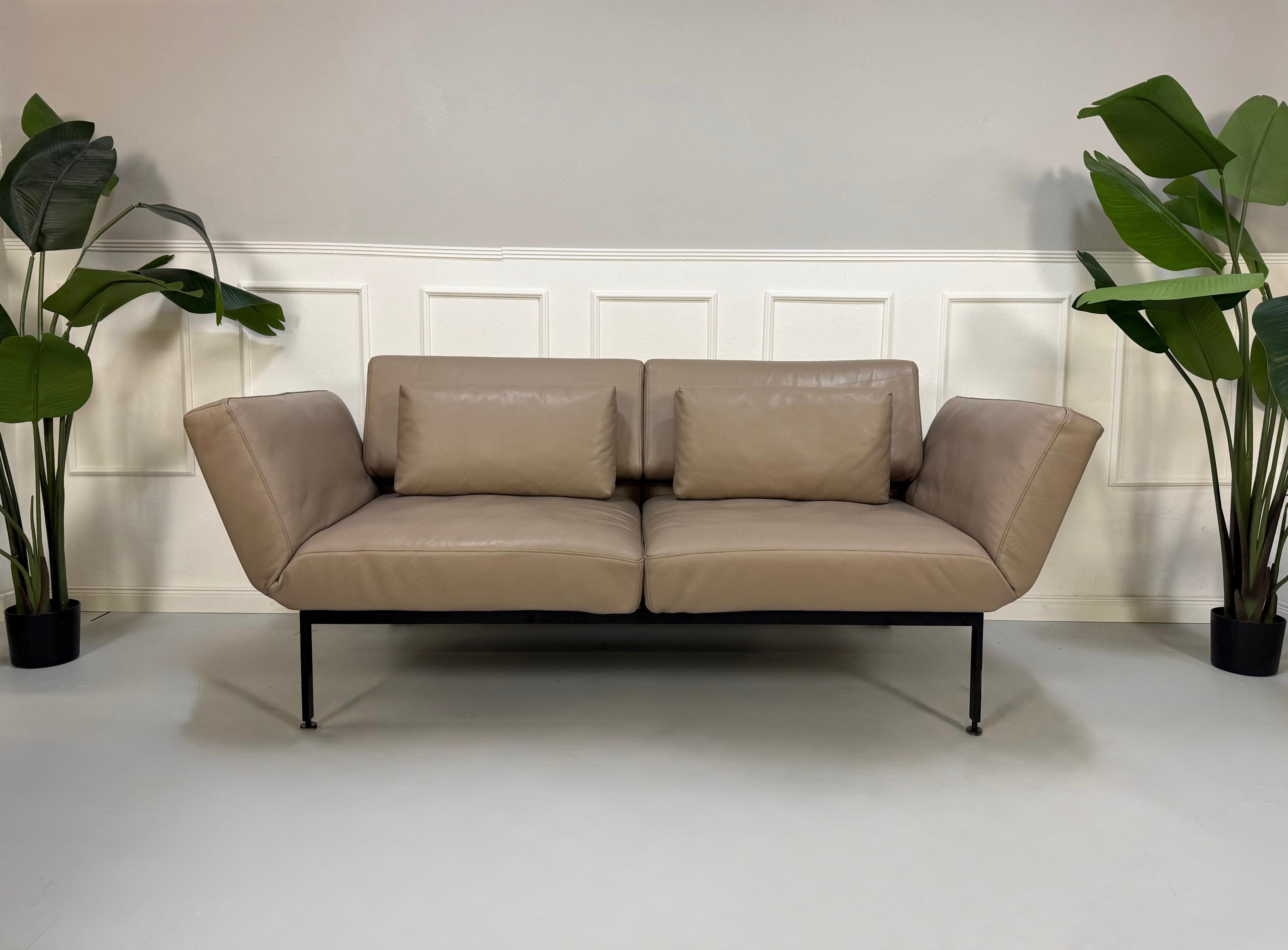 Erneuertes graues Brühl Roro Soft Designer Stoff Sofa vor einer Wand, stilvoll und modern eingerichtet.