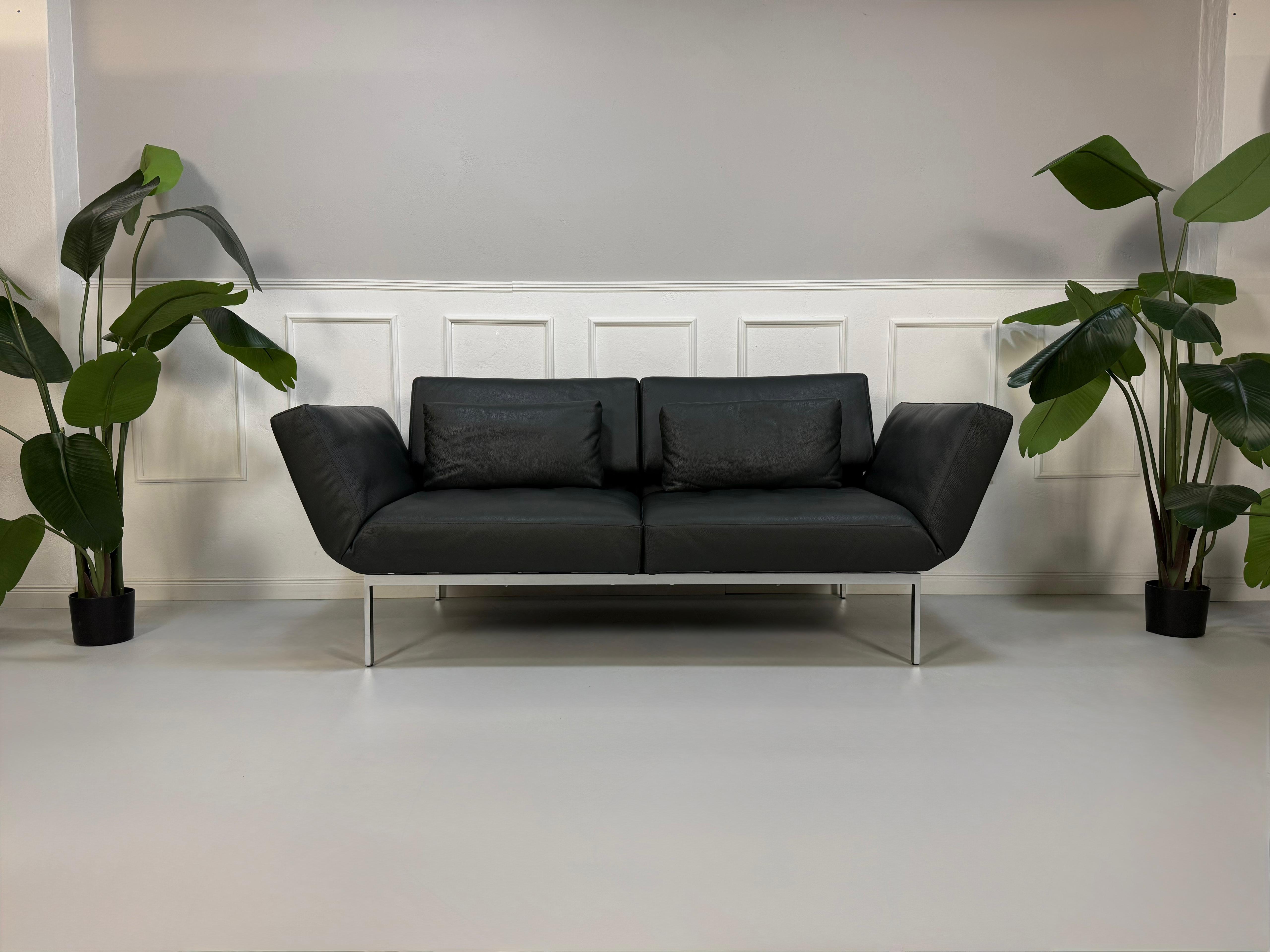 Erneuertes graues Brühl Roro Soft Designer Leder Sofa vor einer Wand, stilvoll und modern eingerichtet.