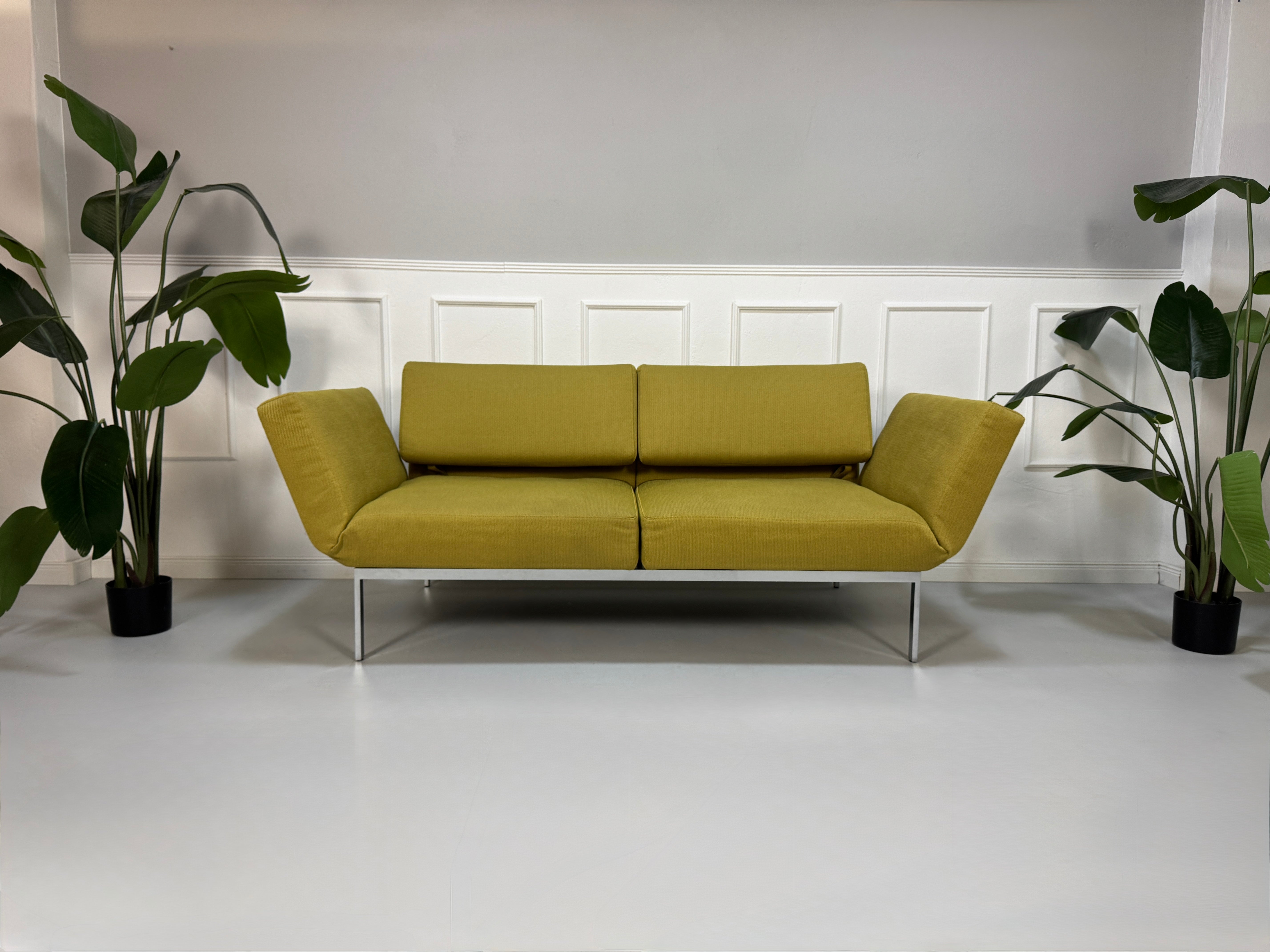 Gebrauchtes grünes Brühl Roro Soft Designer Stoff Sofa vor einer Wand, stilvoll und modern eingerichtet.