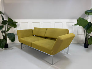 Gebrauchtes grünes Brühl Roro Soft Designer Stoff Sofa vor einer Wand, stilvoll und modern eingerichtet.