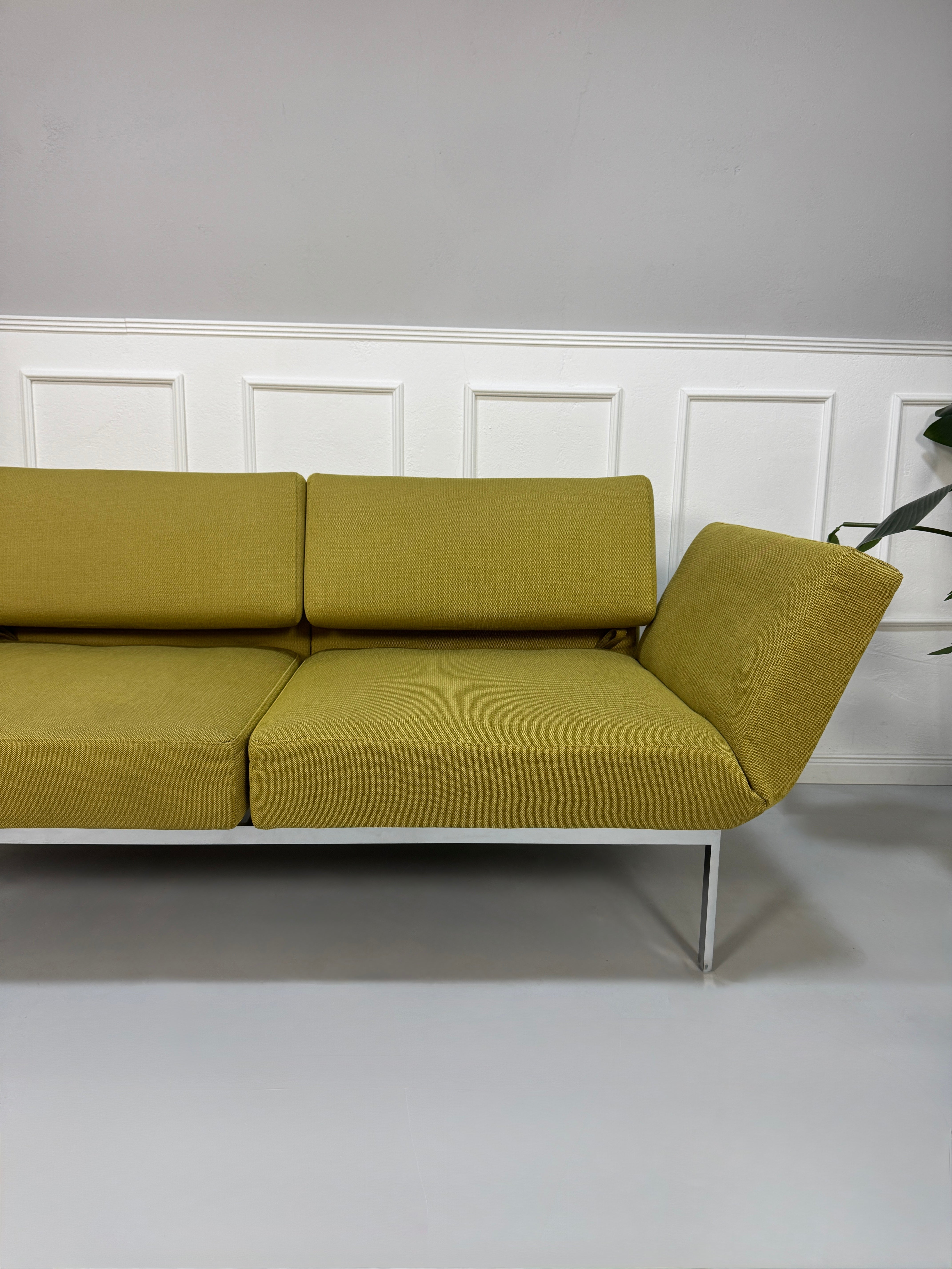 Gebrauchtes grünes Brühl Roro Soft Designer Stoff Sofa vor einer Wand, stilvoll und modern eingerichtet.